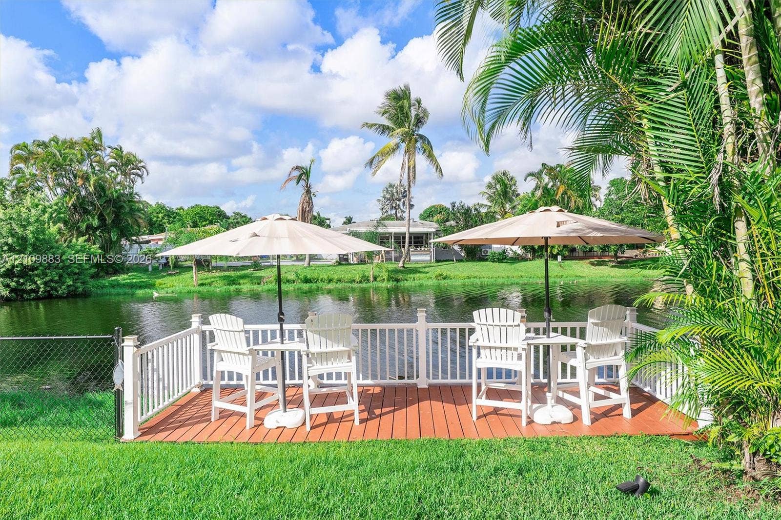 751 SW 54th Avenue, Margate, FL 33068 Waterfront deck featuring wood-finish flooring, white picket railing, and manicured landscaping