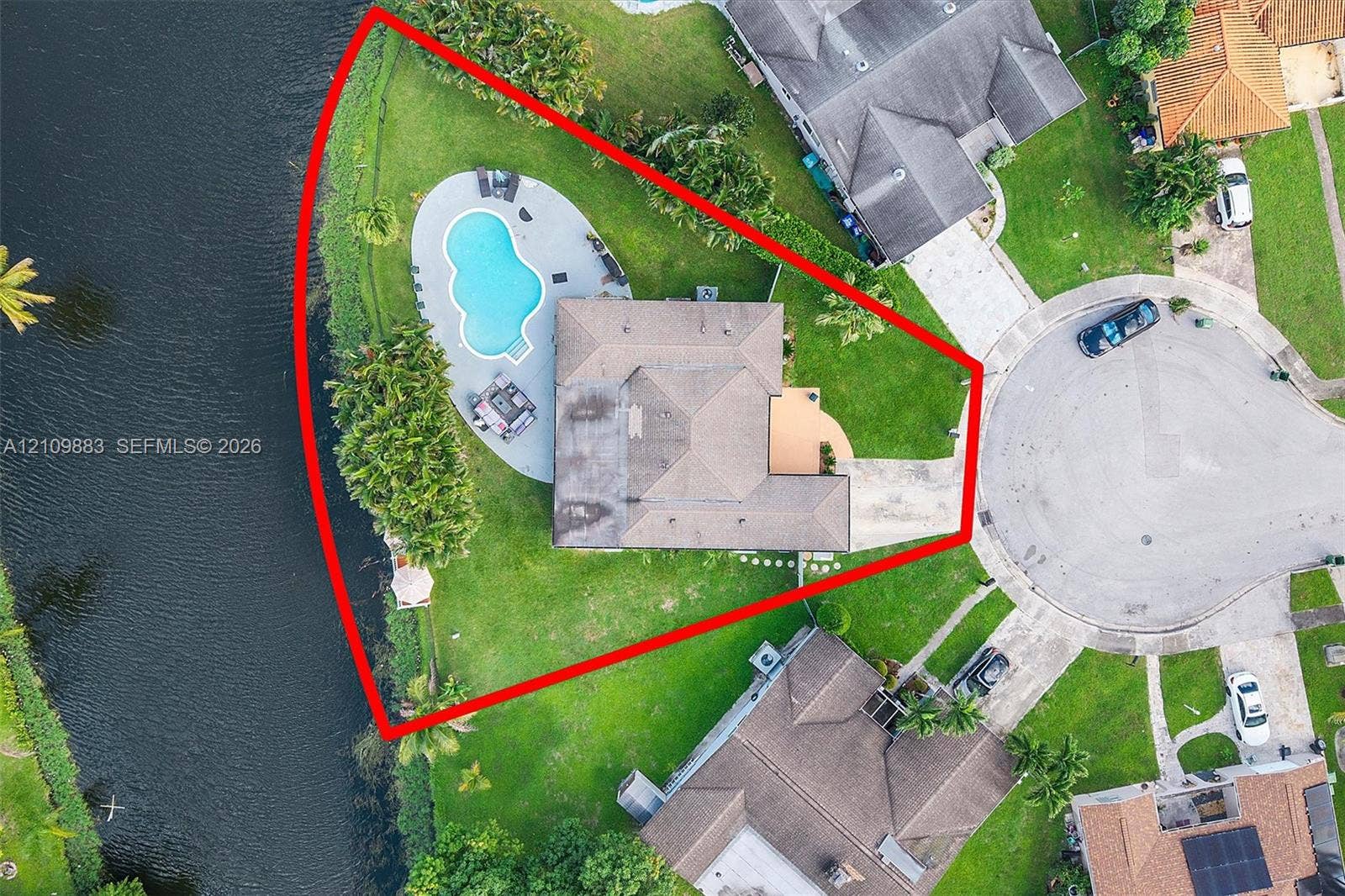 751 SW 54th Avenue, Margate, FL 33068 Waterfront lot on a cul-de-sac featuring a paved driveway, expansive lawn, and an in-ground swimming pool with surrounding deck