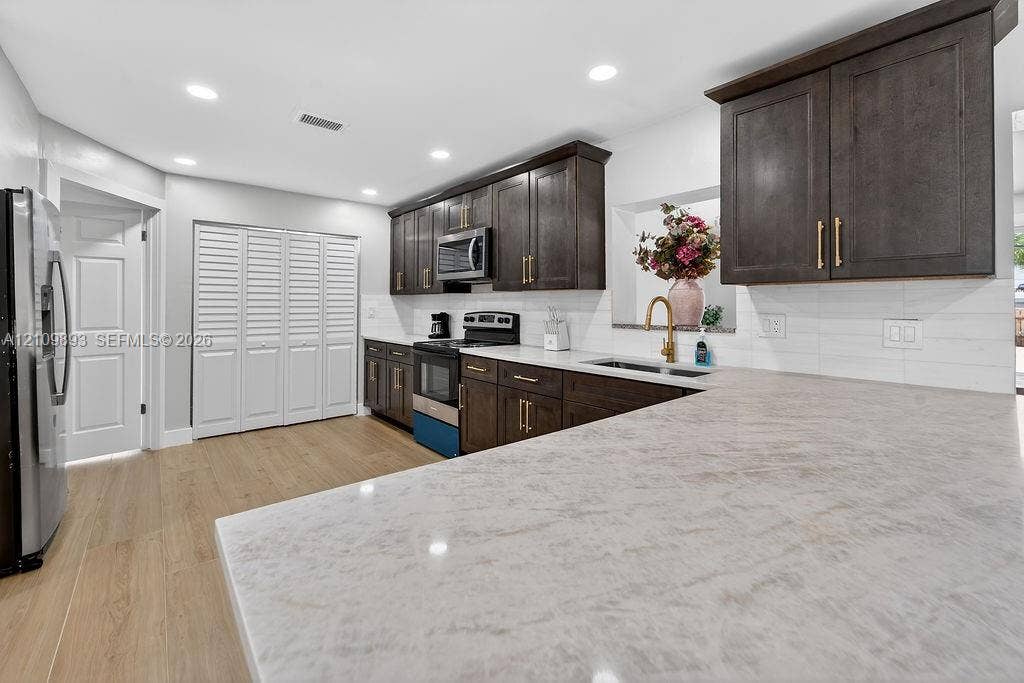 712 Tradewind Drive, North Palm Beach, North Palm Beach, FL 33408 Kitchen featuring dark wood-finish cabinetry, solid-surface countertops, recessed lighting, and wood-finish flooring