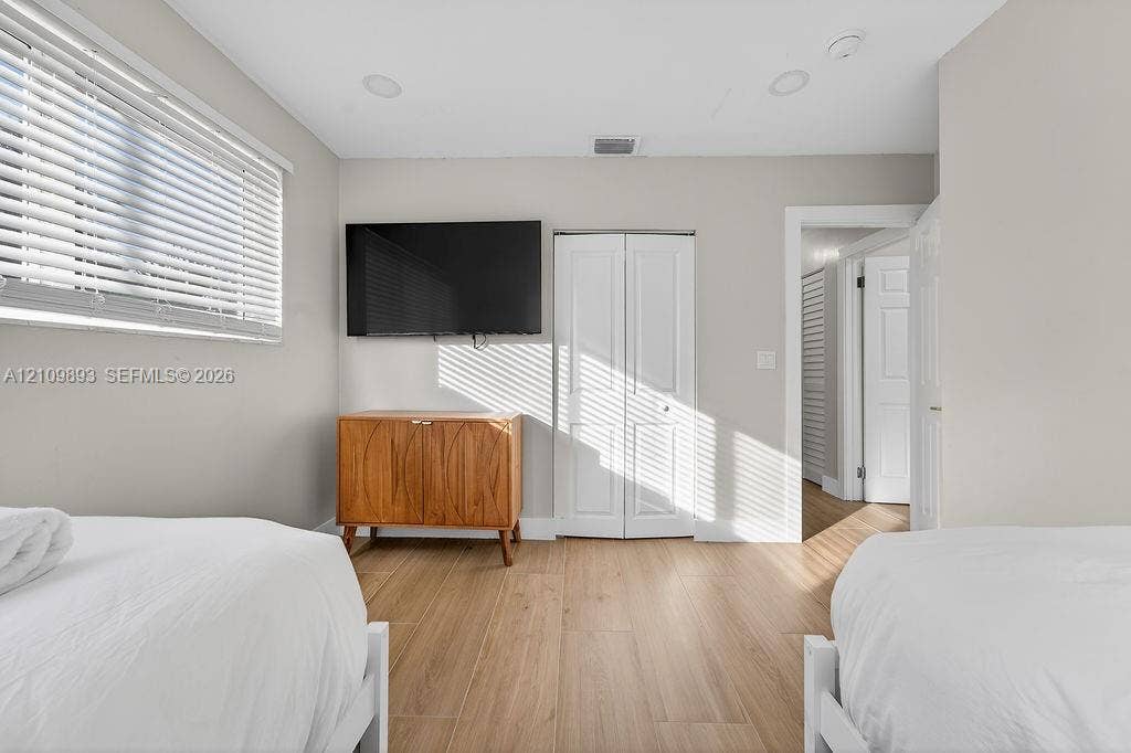 712 Tradewind Drive, North Palm Beach, North Palm Beach, FL 33408 Room featuring wood-finish flooring, white bi-fold closet doors, recessed lighting, and horizontal window blinds