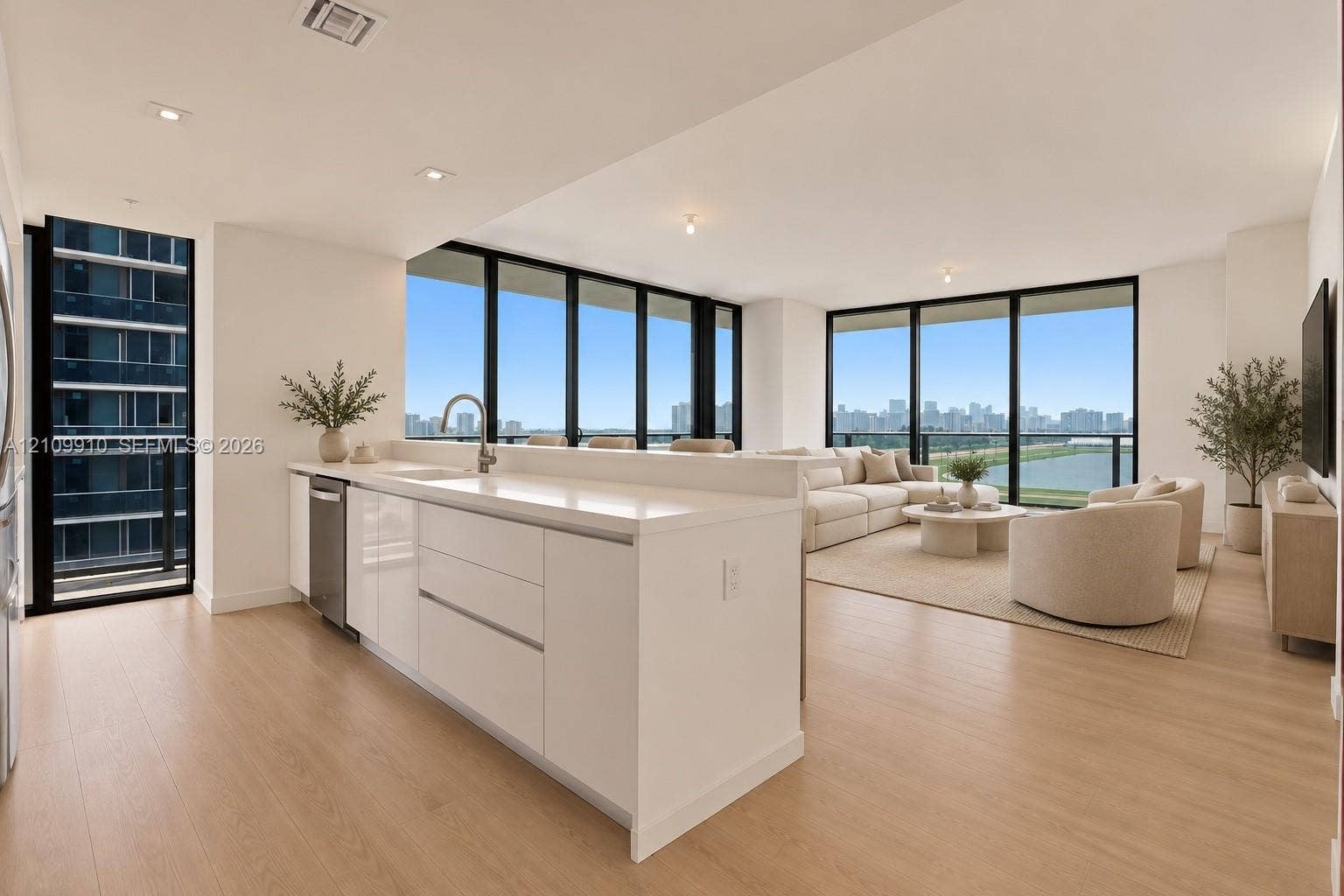 1170 E Hallandale Beach Boulevard, #908, Hallandale Beach, FL 33009 Kitchen featuring white flat-panel cabinetry, light-toned stone countertops, and stainless steel dishwasher, complemented by floor-to-ceiling windows and wood-finish flooring