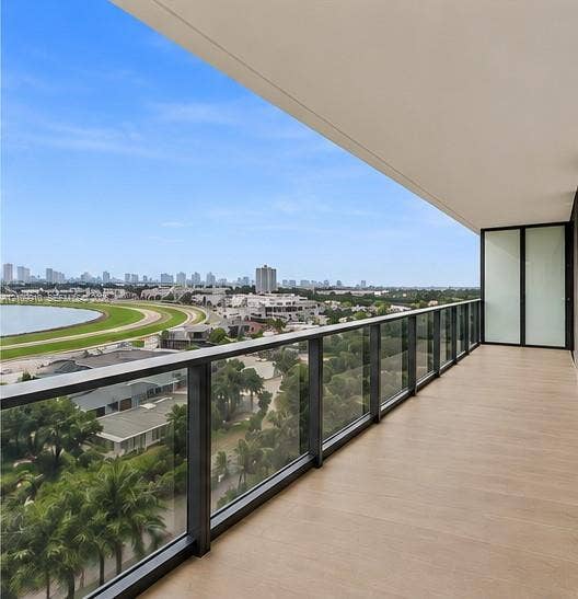 1170 E Hallandale Beach Boulevard, #908, Hallandale Beach, FL 33009 Covered balcony featuring wood-finish flooring, glass panel railing with dark metal framing, and floor-to-ceiling glass door access