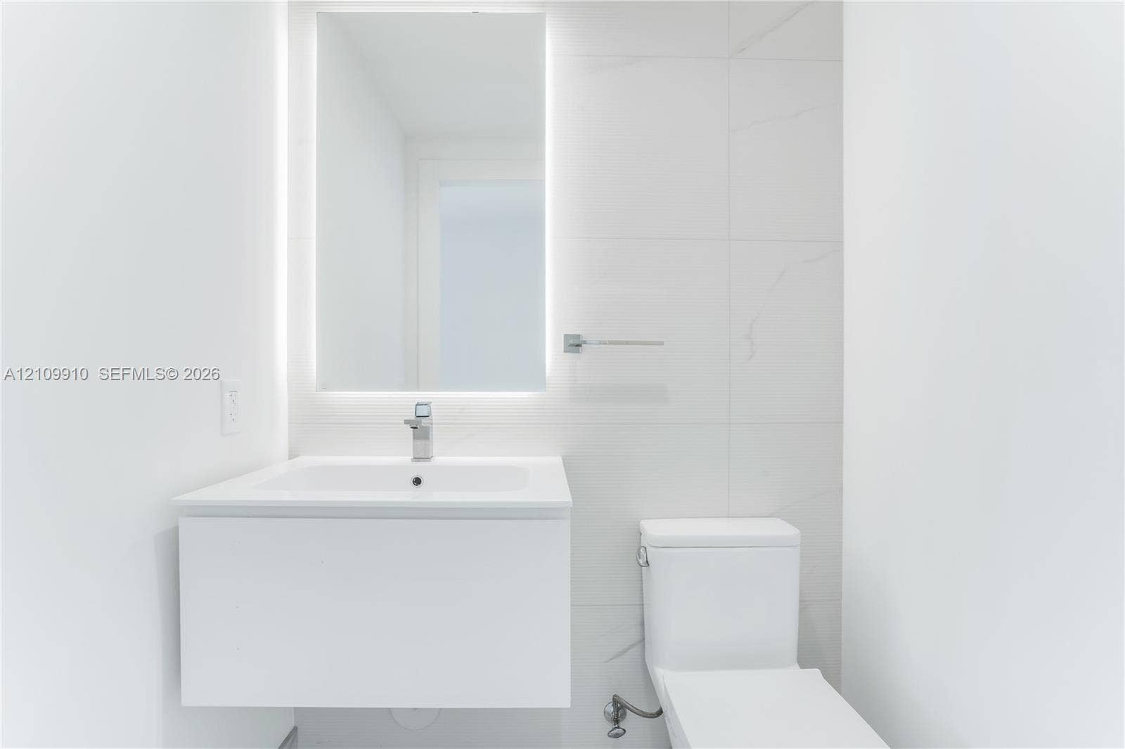 1170 E Hallandale Beach Boulevard, #908, Hallandale Beach, FL 33009 Modern floating vanity with a seamless sink, LED-backlit mirror, and large-format porcelain tile wall cladding