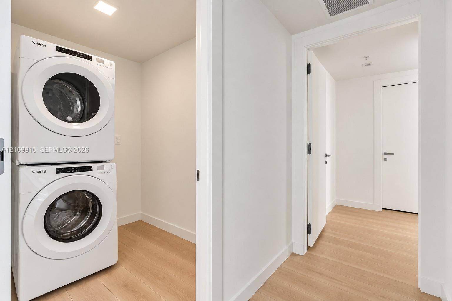 1170 E Hallandale Beach Boulevard, #908, Hallandale Beach, FL 33009 Utility space featuring a stacked white laundry unit, recessed ceiling lighting, and wood-finish flooring