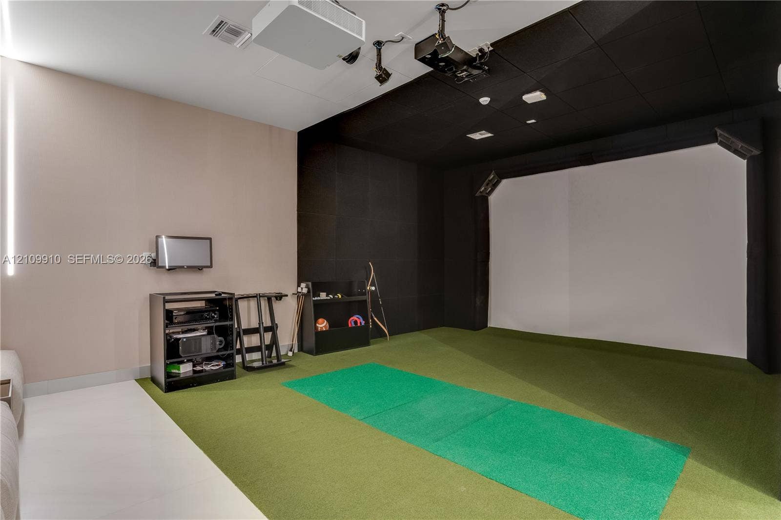 1170 E Hallandale Beach Boulevard, #908, Hallandale Beach, FL 33009 Dedicated simulator room featuring an impact screen, integrated projection system, green turf flooring, and acoustic wall paneling