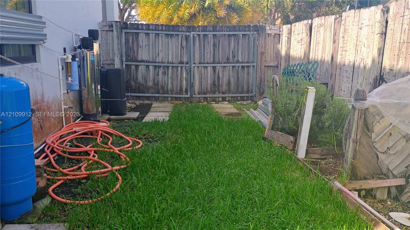 3253 SW 150 Court, Miami, FL 33185 Outdoor area featuring a wood privacy fence, double-gate access, concrete paver path, and lawn space