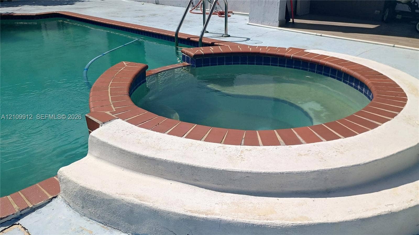 3253 SW 150 Court, Miami, FL 33185 In-ground swimming pool featuring a circular spillover spa, brick coping, and concrete pool deck