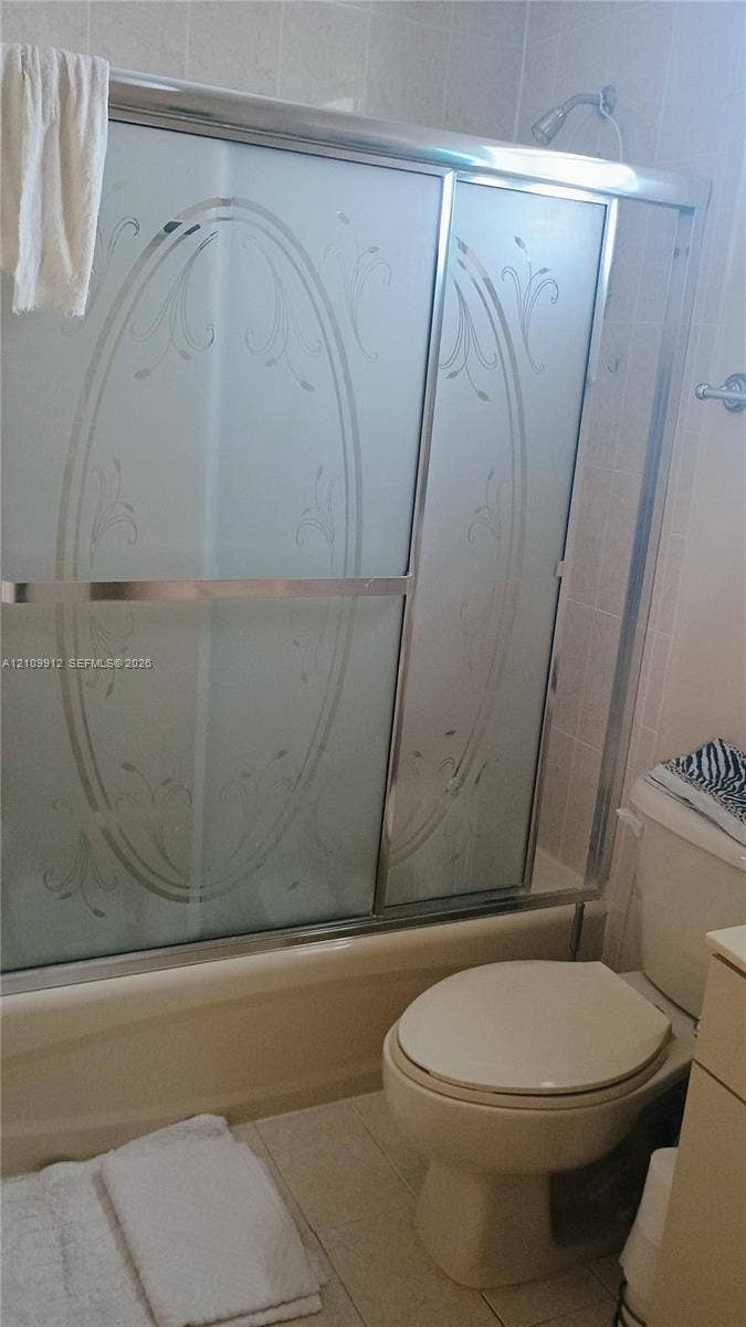 3253 SW 150 Court, Miami, FL 33185 Bathtub and shower combination featuring sliding frosted glass doors with etched detailing, chrome-finished hardware, and tile wall surround