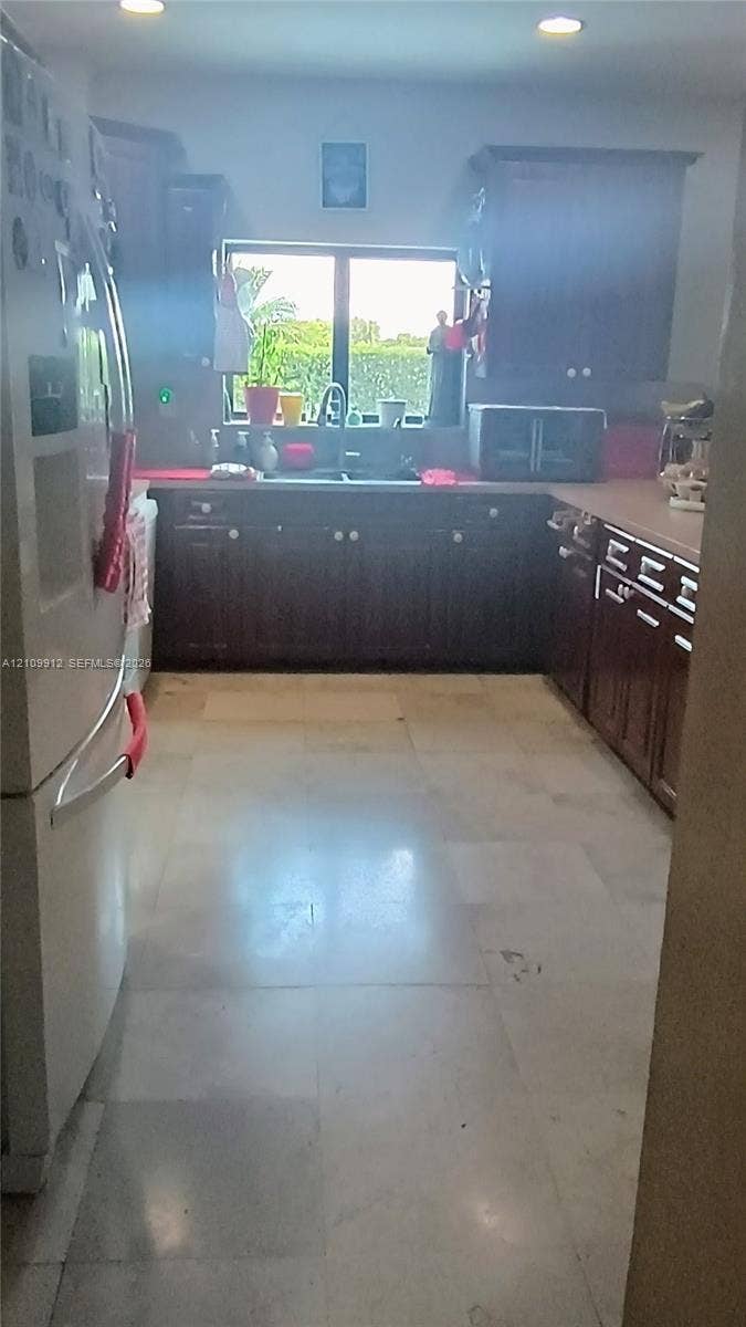 3253 SW 150 Court, Miami, FL 33185 Kitchen featuring dark-finish cabinetry, neutral tile flooring, recessed ceiling lighting, and a double-basin sink positioned beneath a window