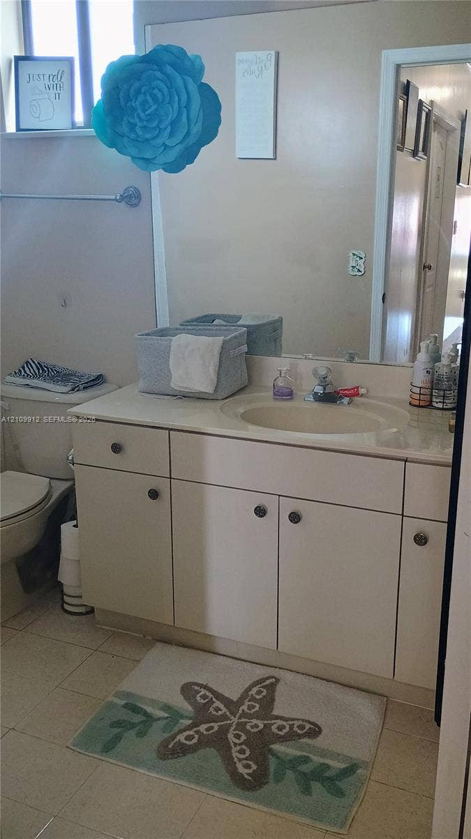 3253 SW 150 Court, Miami, FL 33185 Vanity with integrated sink and countertop, full-width wall mirror, and neutral tile flooring
