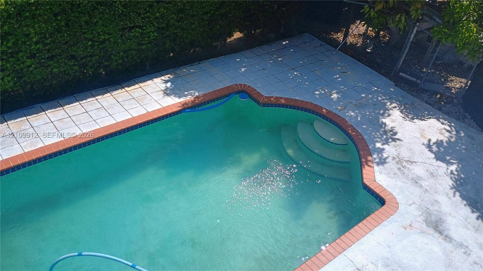 3253 SW 150 Court, Miami, FL 33185 In-ground pool featuring a brick coping border and concrete surround with integrated entry steps