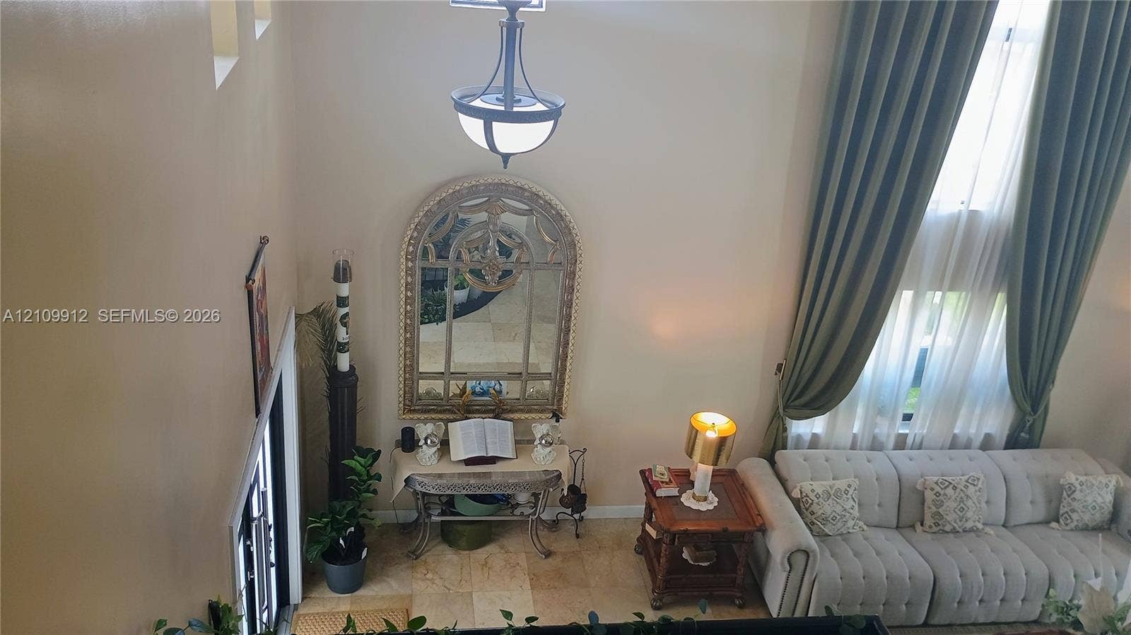 3253 SW 150 Court, Miami, FL 33185 Double-height ceiling, floor-to-ceiling drapery, stone-finish tile flooring, and decorative wrought-iron chandelier
