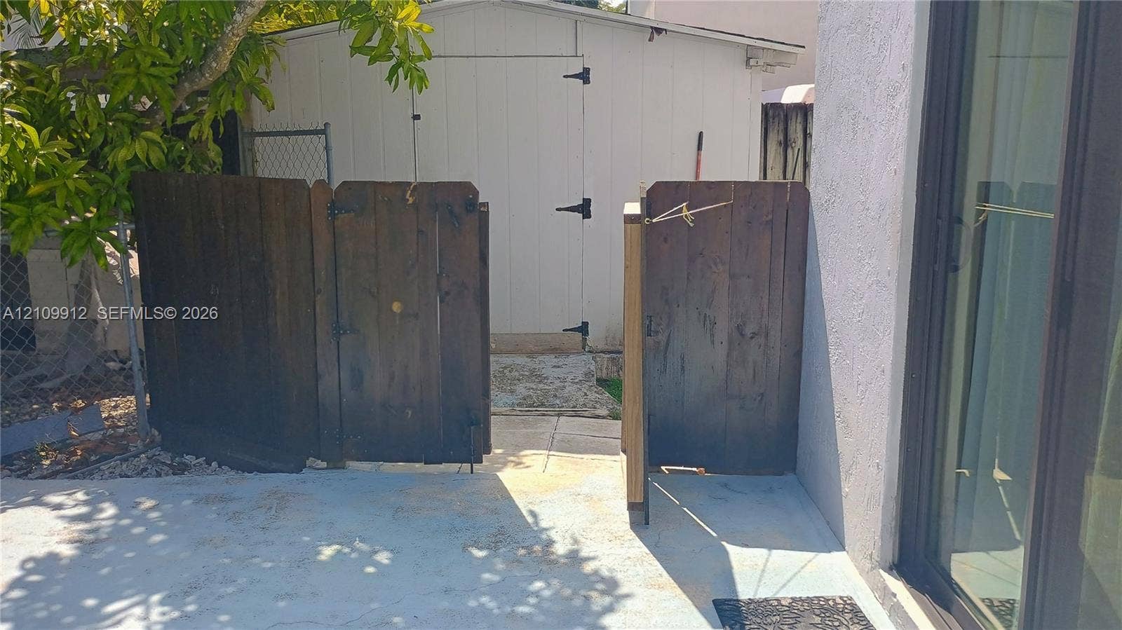 3253 SW 150 Court, Miami, FL 33185 Exterior area featuring a concrete patio, wood-paneled privacy gate, and a detached storage shed