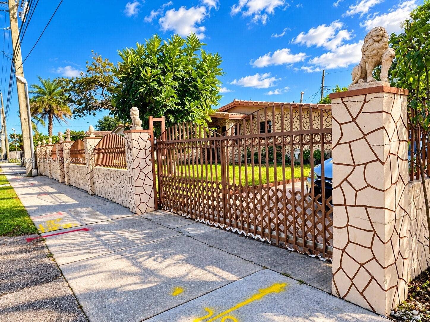 1440 NW 183rd Street, #0, Miami Gardens, Miami Gardens, FL 33169 Fenced perimeter featuring stone-clad masonry pillars topped with decorative stone lion accents, complemented by a tall metal lattice gate