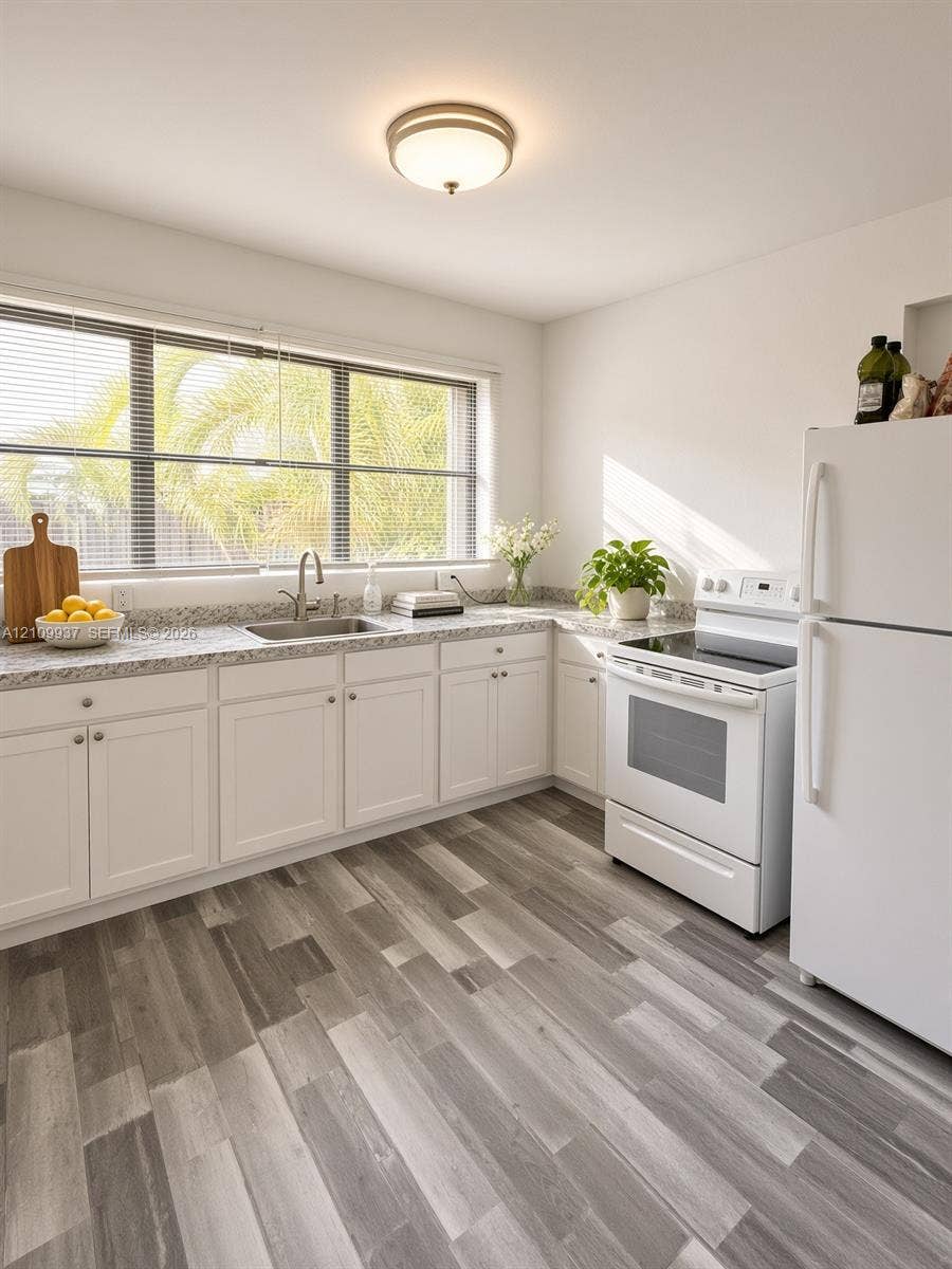 1024 Tyler Street, #2, Hollywood, Hollywood, FL 33019 Kitchen featuring white cabinetry, stone-finish countertops, wood-finish flooring, a stainless steel undermount sink with a gooseneck faucet, and a large horizontal window