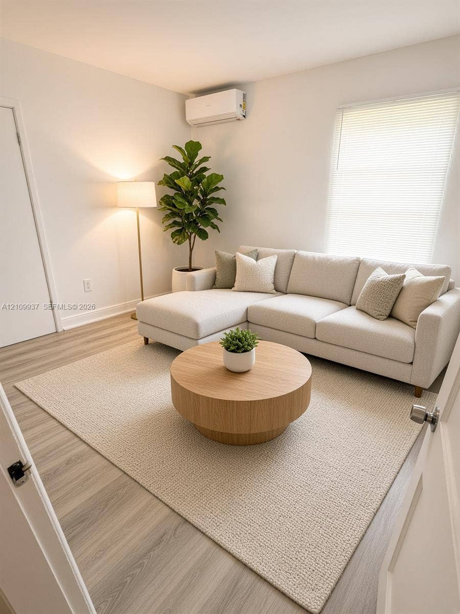 1024 Tyler Street, #2, Hollywood, Hollywood, FL 33019 Neutral-toned interior featuring wood-finish flooring, a wall-mounted ductless climate control unit, and a window with horizontal blinds