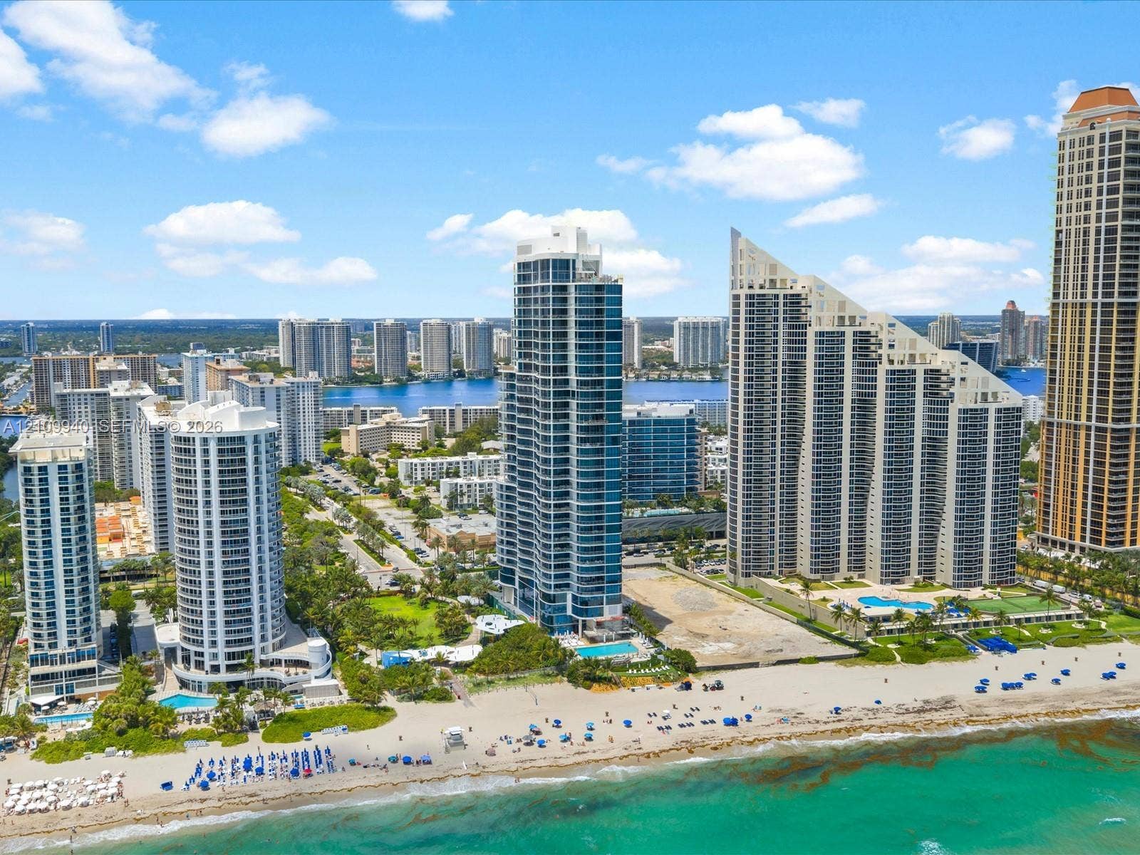 High-rise coastal towers featuring floor-to-ceiling glass facades, direct beach access, and ground-level swimming pools