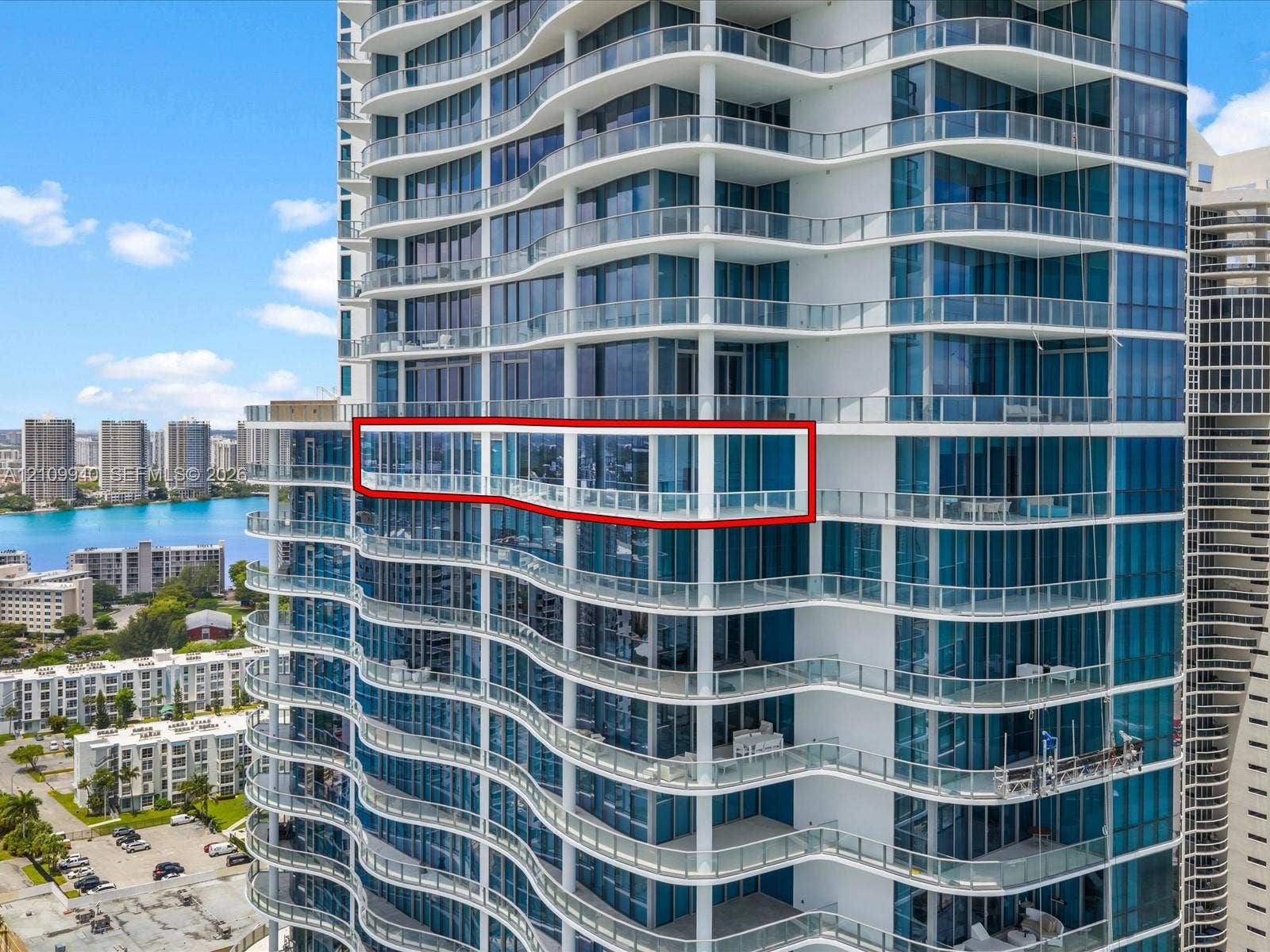 High-rise exterior featuring floor-to-ceiling glass windows and a wrap-around balcony with glass railings