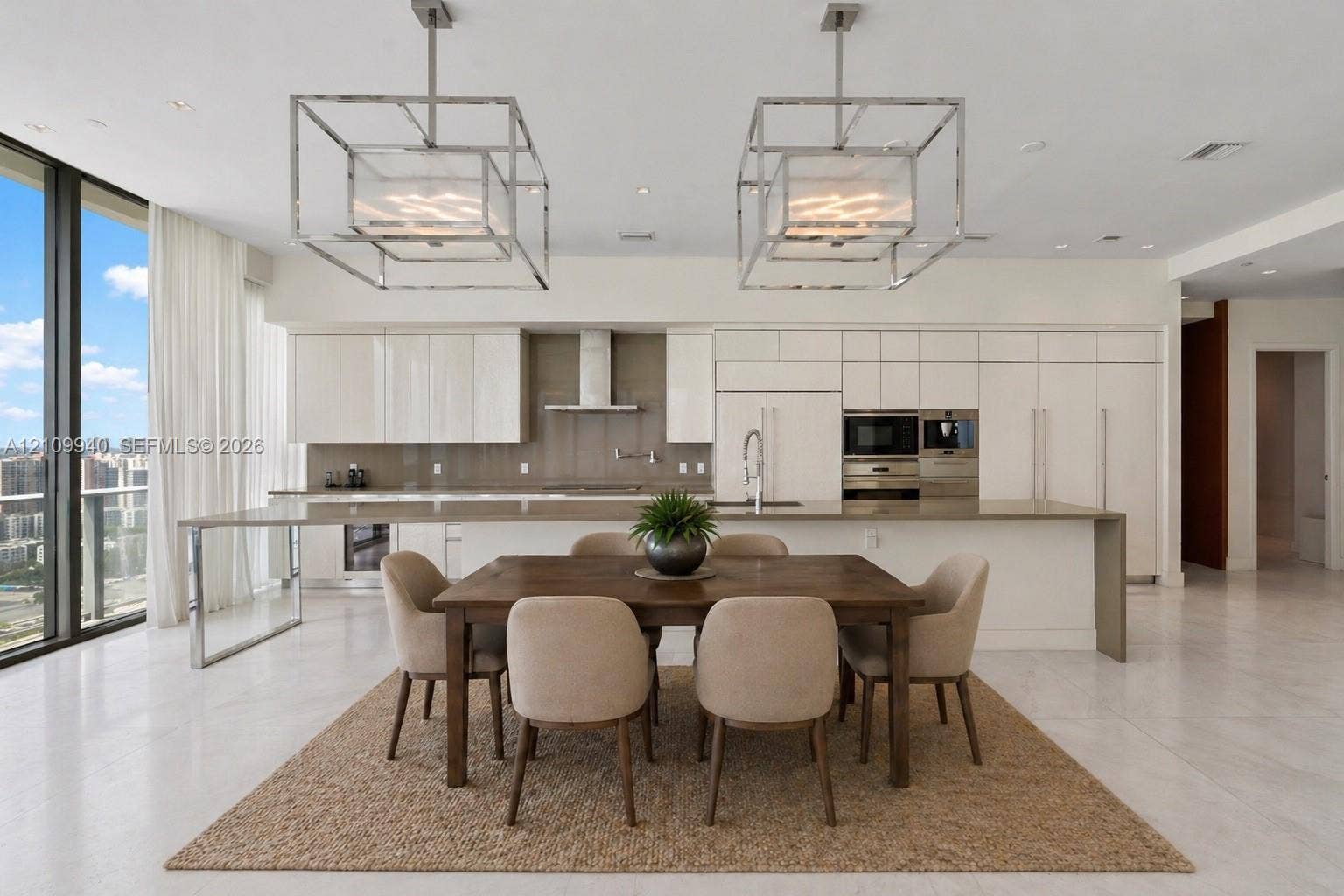 Contemporary kitchen featuring high-gloss cabinetry, stone-finish countertops, stainless steel appliances, floor-to-ceiling windows, and geometric metal pendant lighting