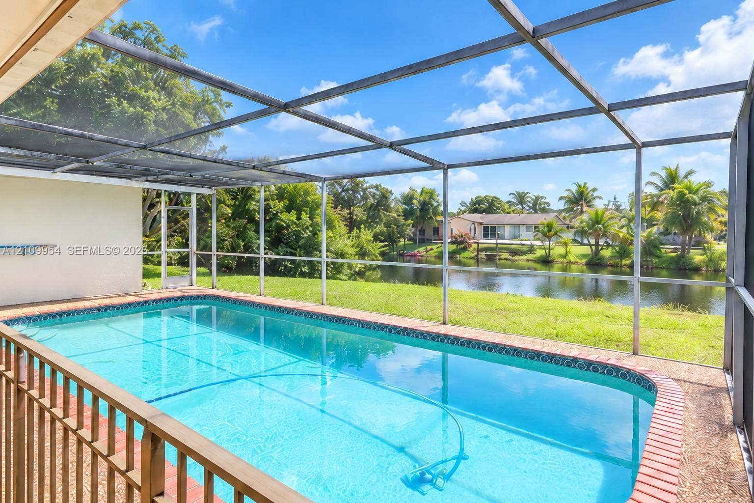 8528 Windsor Drive, Miramar, FL 33025 Screen-enclosed swimming pool featuring a brick paver perimeter and direct water frontage