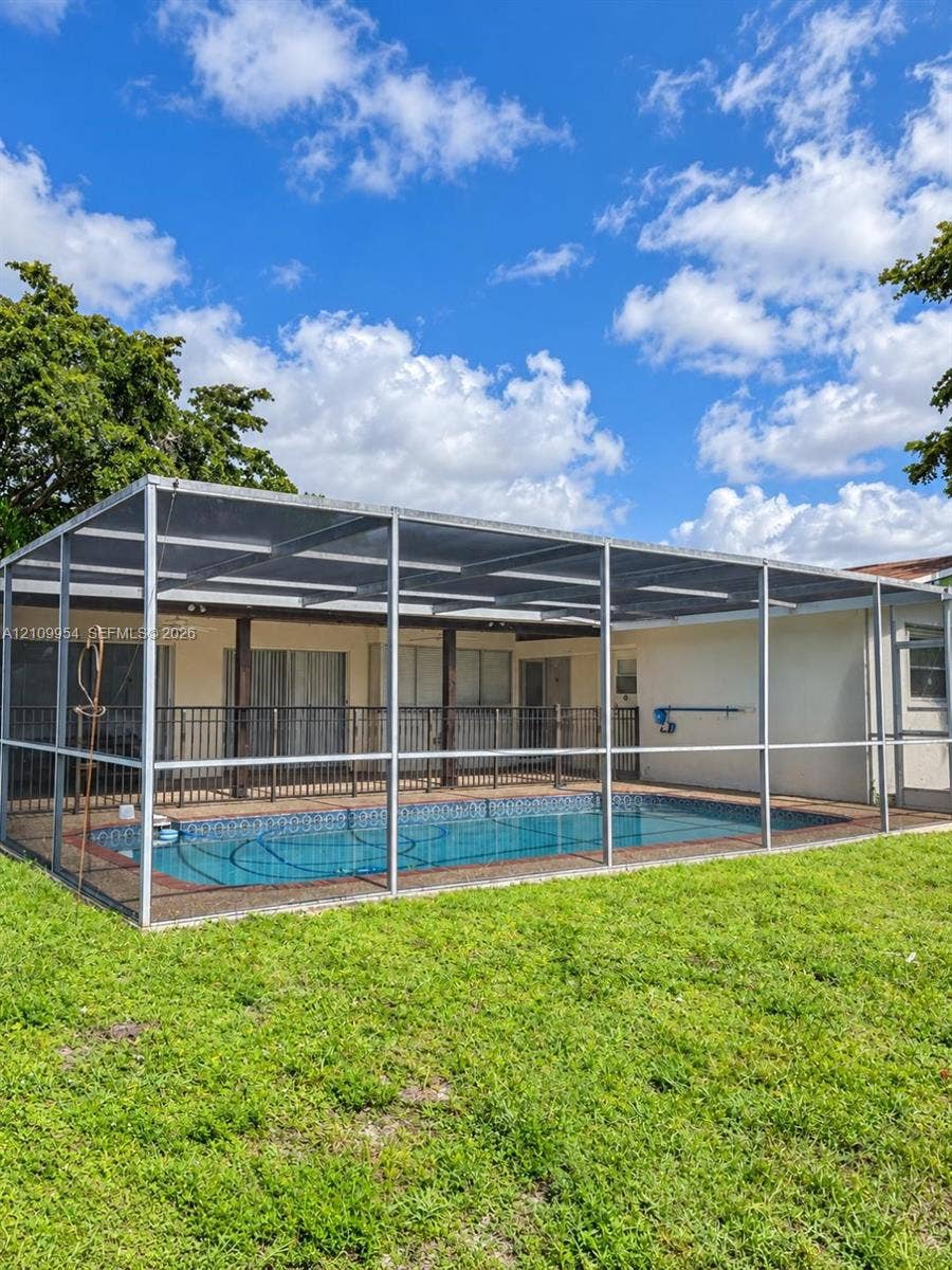 8528 Windsor Drive, Miramar, FL 33025 In-ground swimming pool enclosed by a screen lanai, featuring a concrete patio and open green space