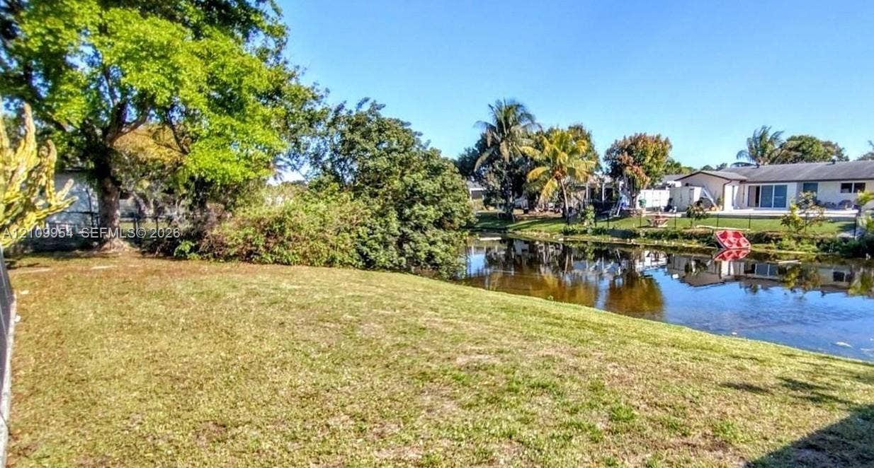 8528 Windsor Drive, Miramar, FL 33025 Expansive backyard featuring a grass lawn, mature trees, and direct water frontage