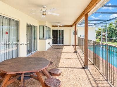 8528 Windsor Drive, Miramar, FL 33025 Covered patio featuring an aggregate concrete floor, ceiling fans, wood-support columns, and a screened enclosure surrounding a swimming pool