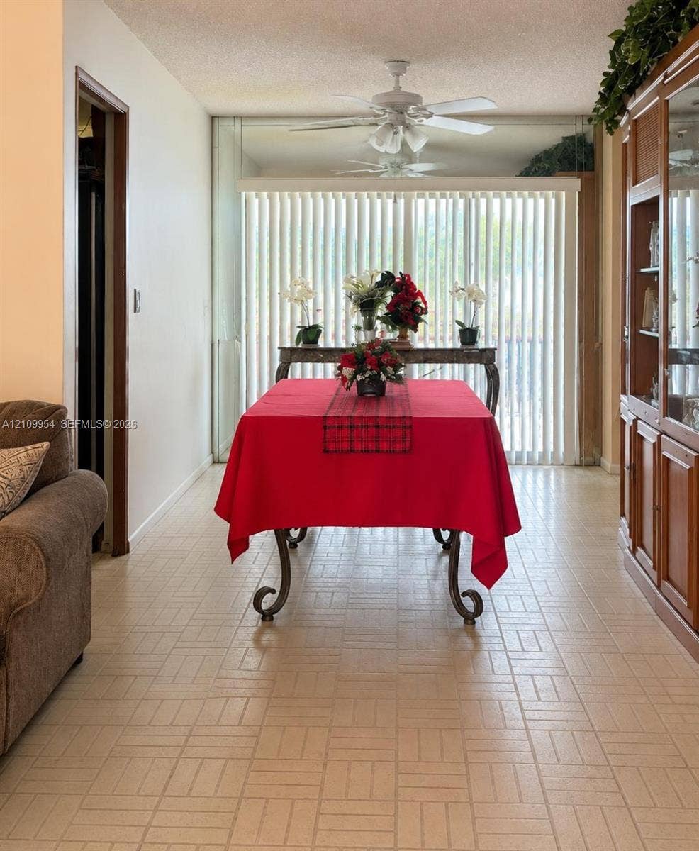 8528 Windsor Drive, Miramar, FL 33025 Ceramic tile flooring, built-in wooden cabinetry with glass-front shelving, ceiling-mounted light fixtures with integrated fans, and full-height vertical window blinds