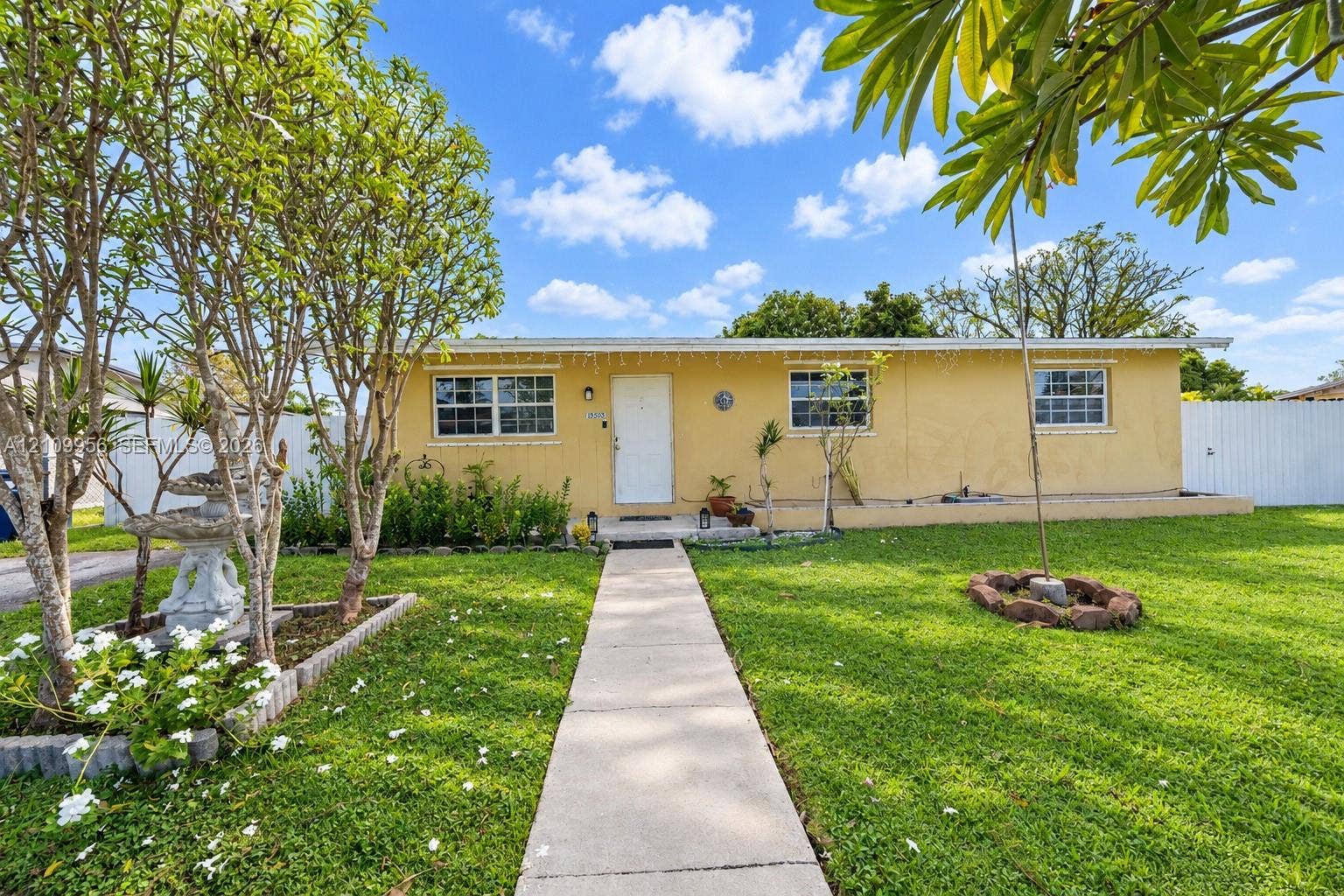 19503 SW 114th Place, Miami, FL 33157 Single-story exterior featuring a stucco facade, concrete walkway, and white privacy fencing