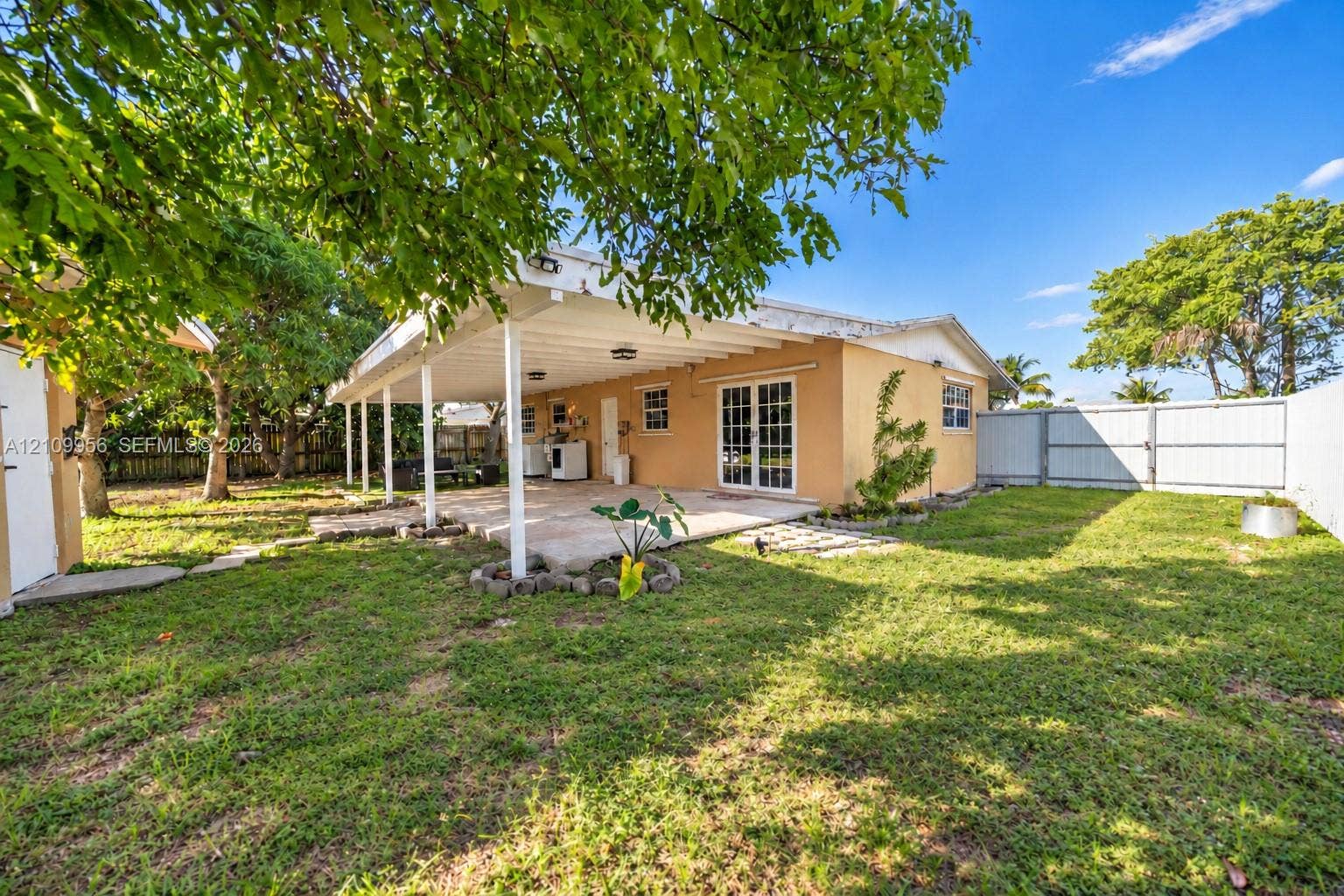 19503 SW 114th Place, Miami, FL 33157 Backyard featuring a covered patio, concrete hardscaping, mature trees, and perimeter fencing