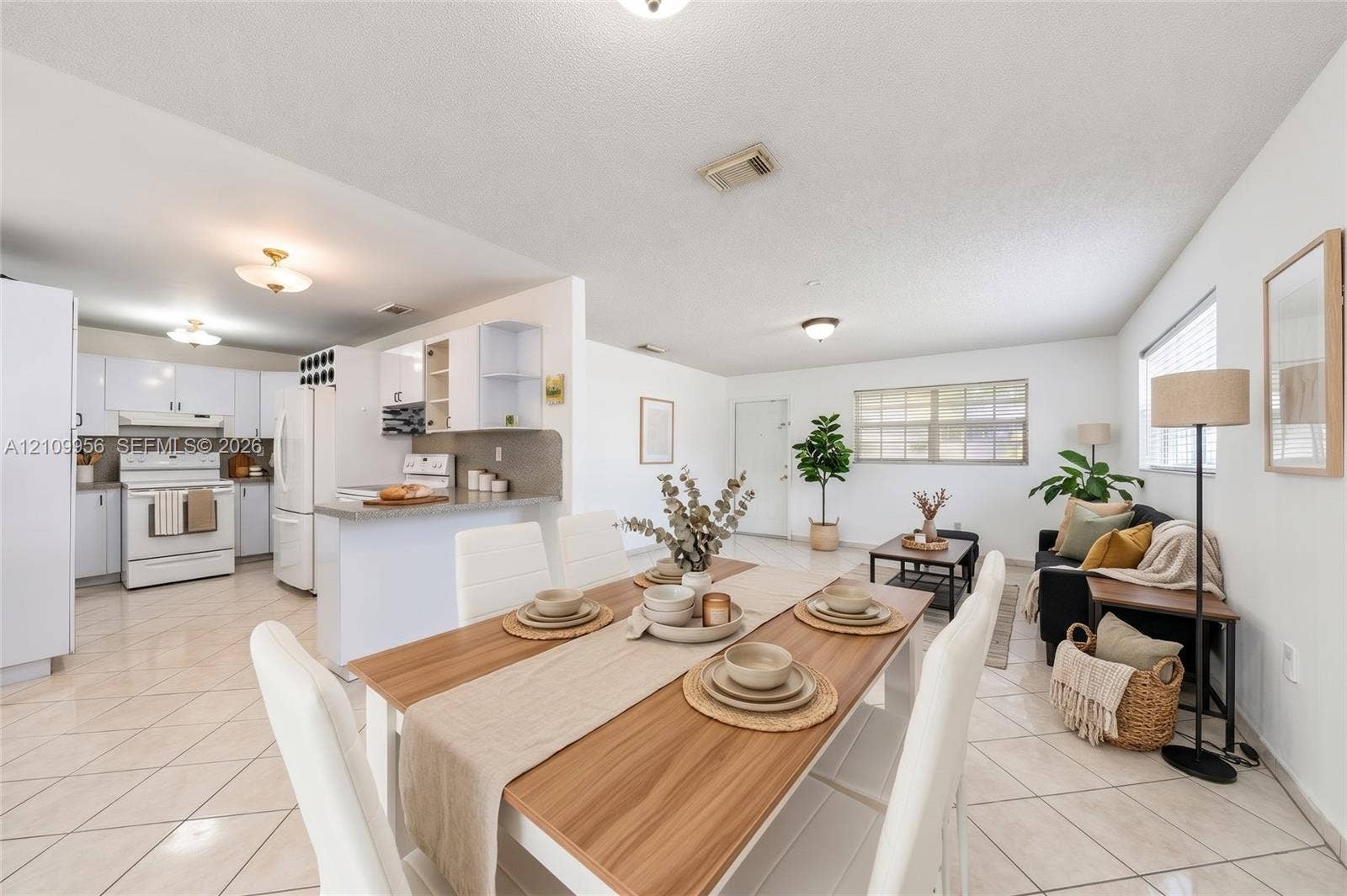 19503 SW 114th Place, Miami, FL 33157 Open-concept interior featuring light-colored tile flooring, white cabinetry, integrated peninsula breakfast bar, and multiple flush-mount light fixtures