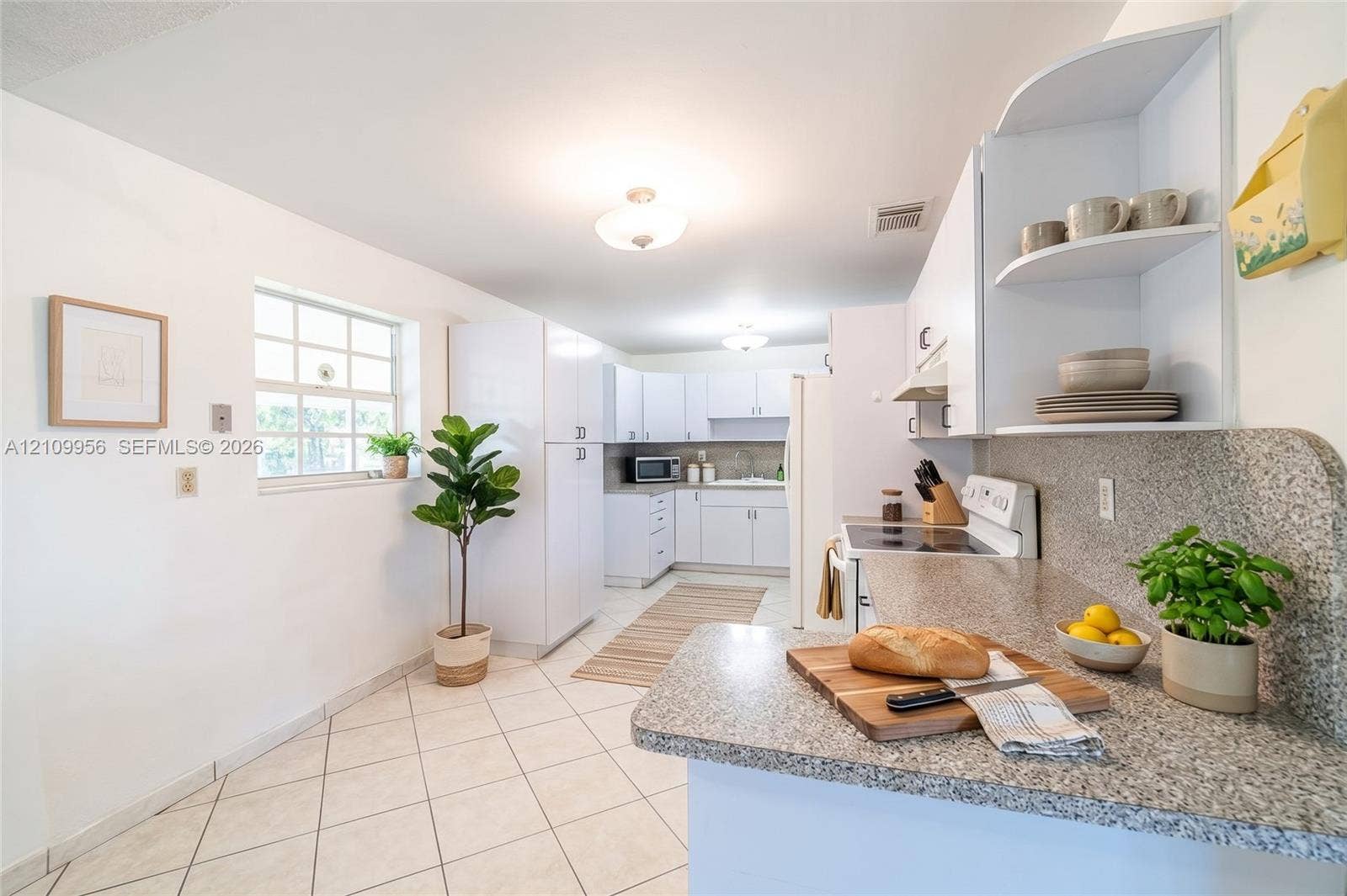 19503 SW 114th Place, Miami, FL 33157 Kitchen featuring white cabinetry, solid surface countertops, a grid-pattern window, and neutral tile flooring