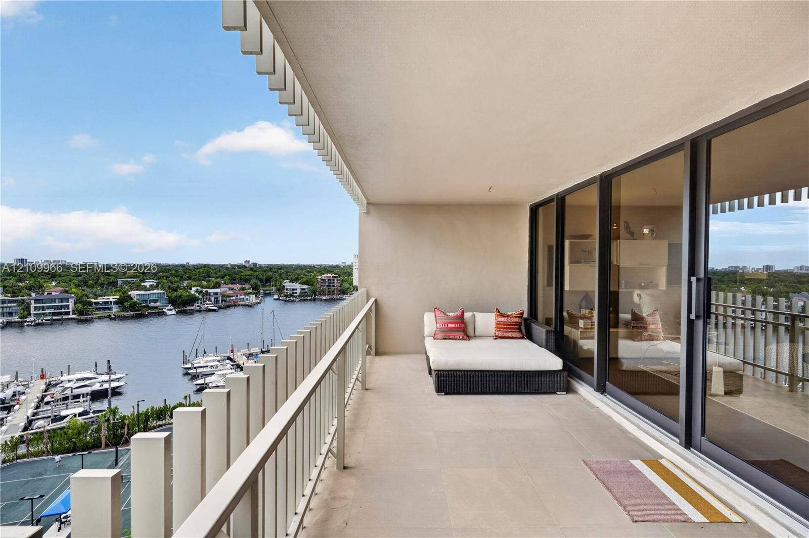 Covered balcony featuring tile flooring, metal railing, and floor-to-ceiling glass sliding doors