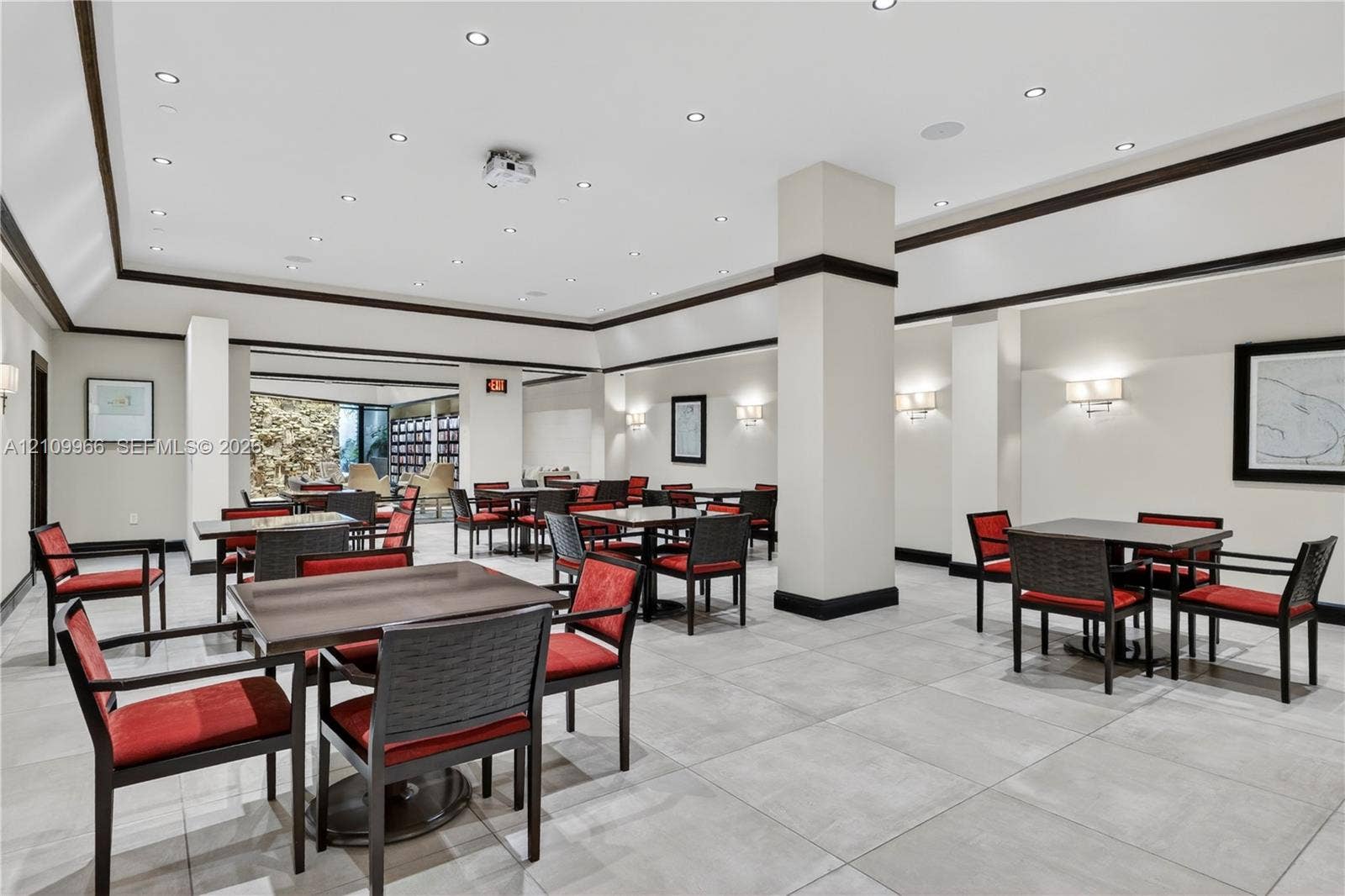 Large common area featuring neutral tile flooring, recessed lighting, crown molding with dark wood trim, structural support columns, and wall-mounted sconces