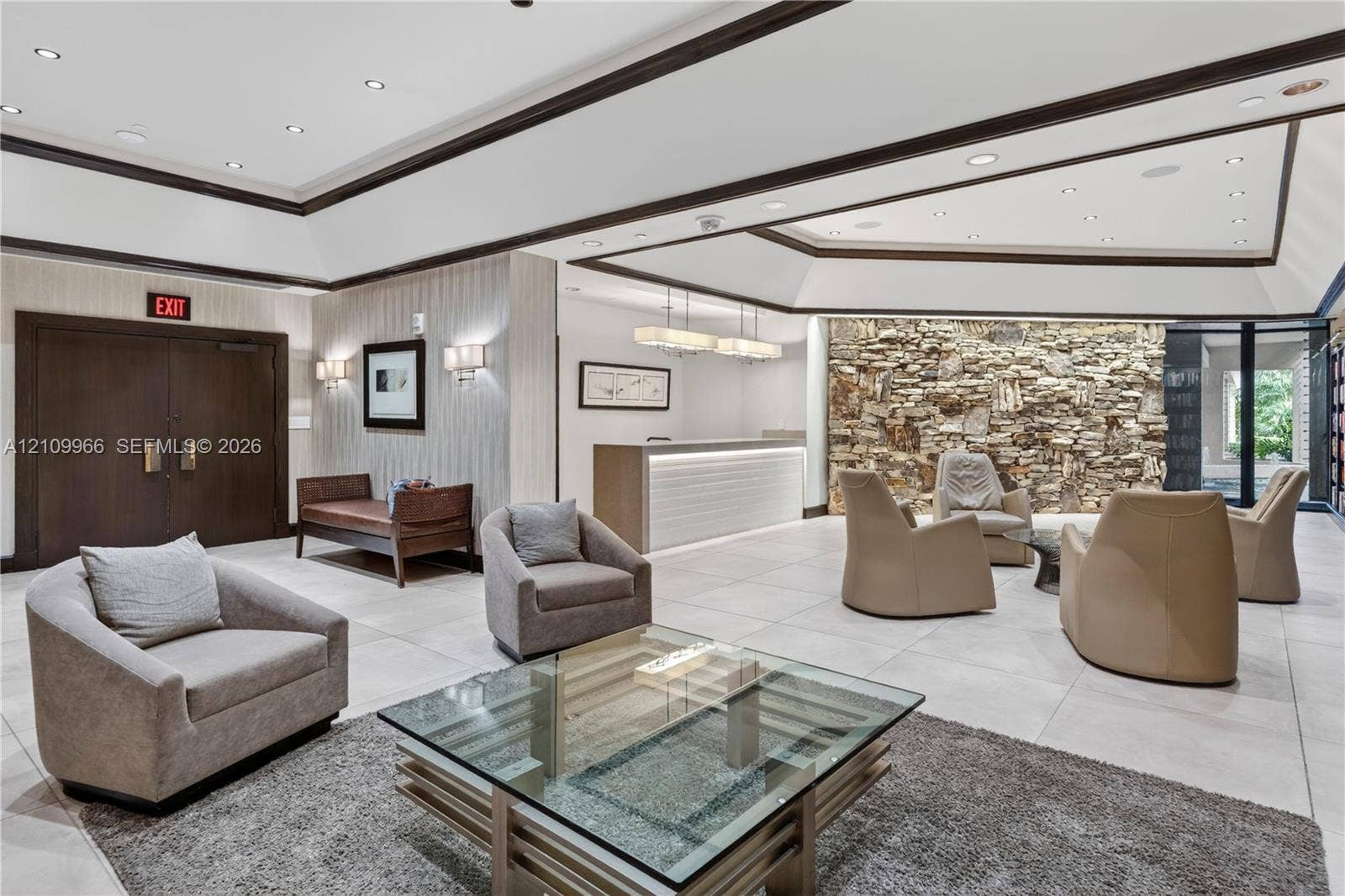 Reception area featuring an expansive tray ceiling, stone-accented wall, recessed lighting, tile flooring, and custom built-in service desk