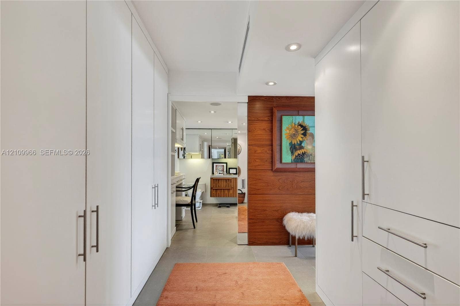 Floor-to-ceiling built-in white cabinetry, accent wall with horizontal wood paneling, recessed lighting, and large-format neutral tile flooring