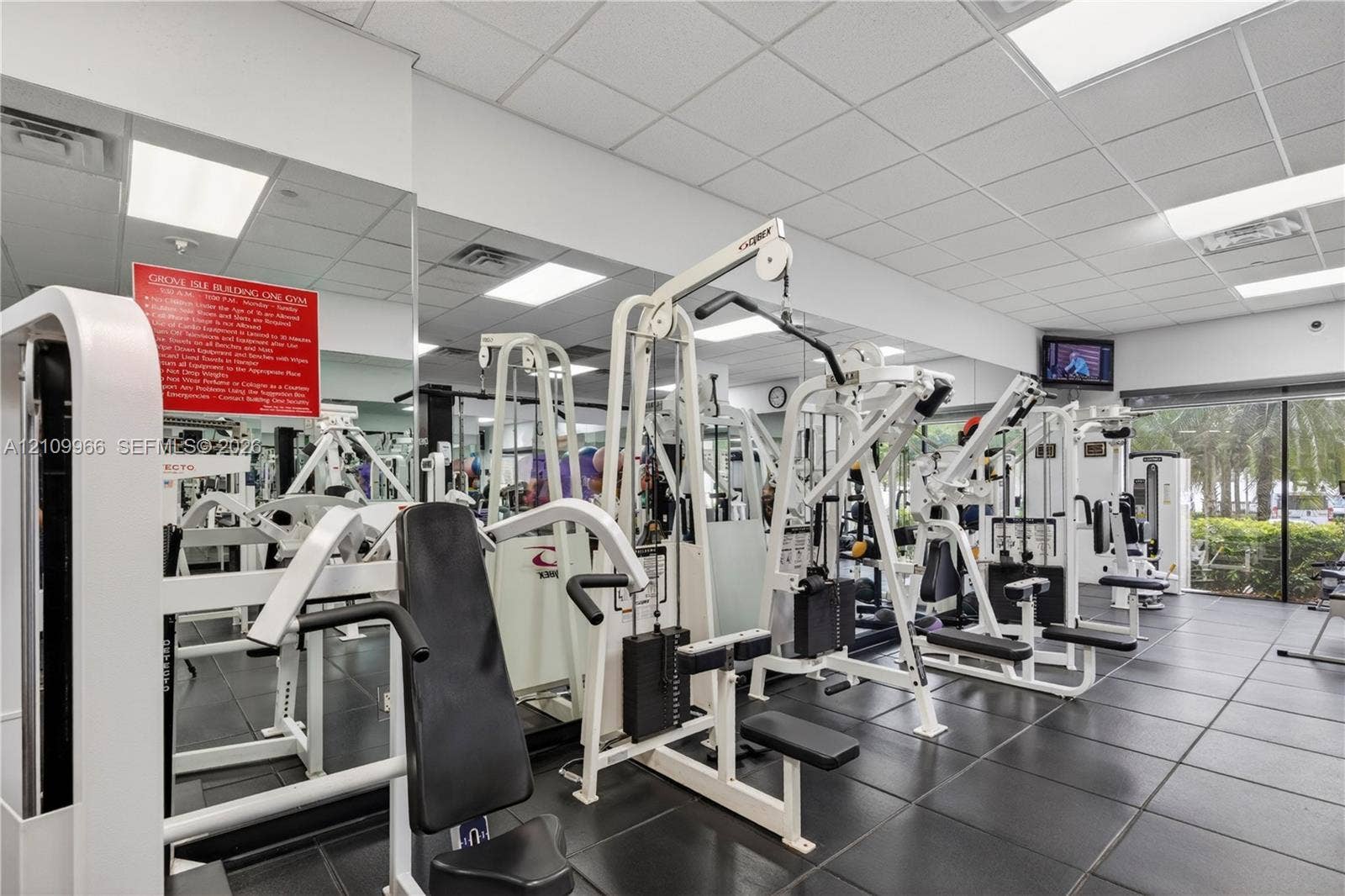 Fitness center featuring modular rubber flooring, full-wall mirrors, recessed drop-ceiling lighting, and floor-to-ceiling windows