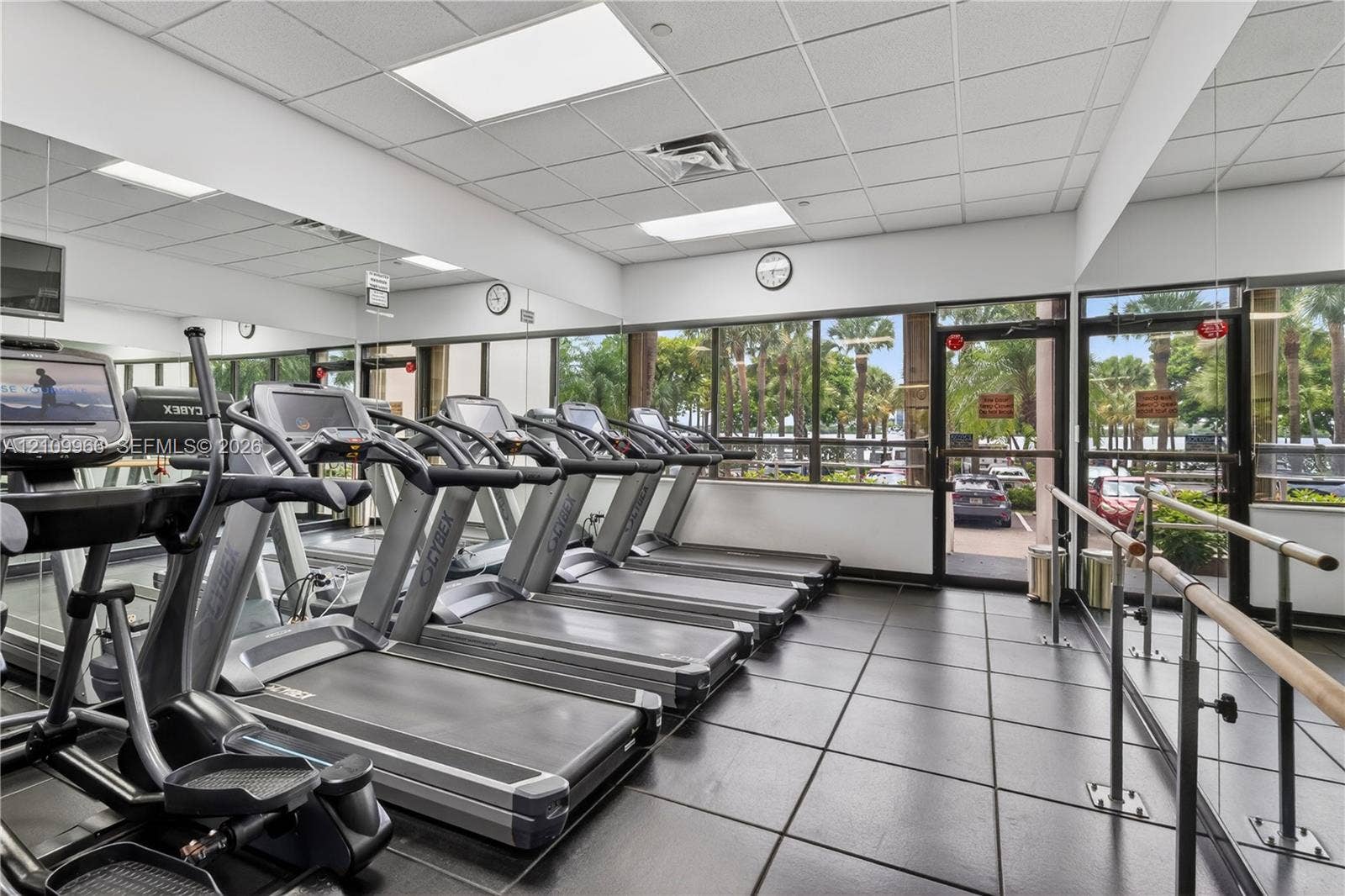 Fitness center featuring large-format tile flooring, floor-to-ceiling mirrored walls, and expansive windows