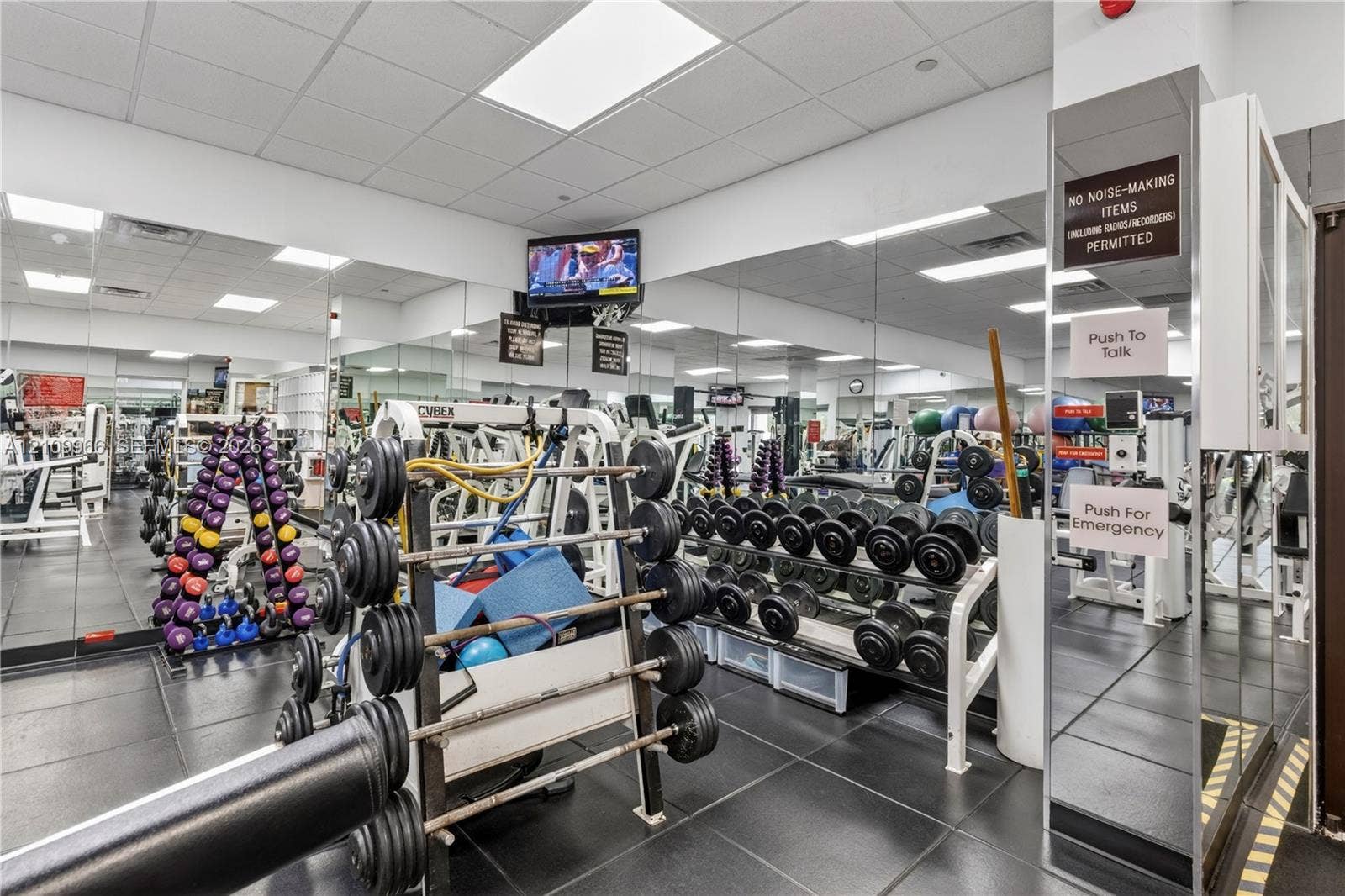 Fitness facility featuring mirrored walls, rubberized flooring, and built-in weight storage racks