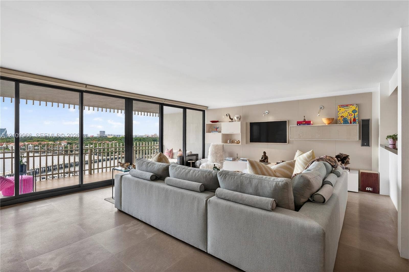 Floor-to-ceiling sliding glass doors, expansive private balcony with metal railing, large-format tile flooring, and custom built-in wall cabinetry