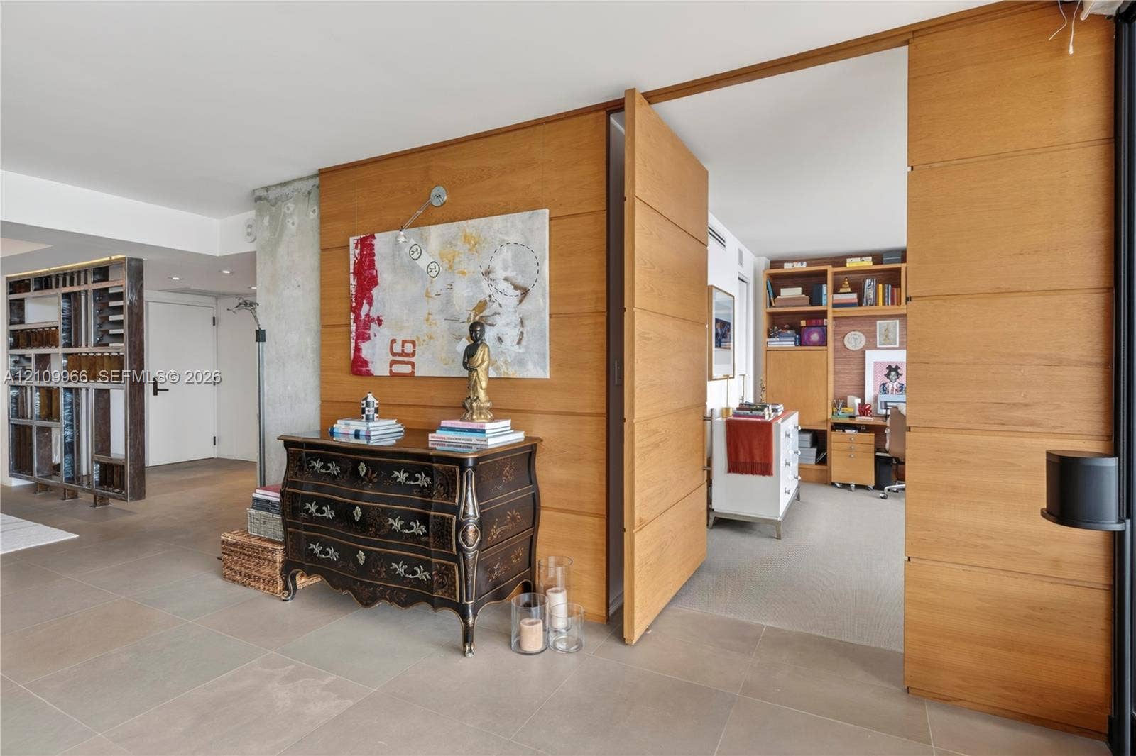 Floor-to-ceiling wood paneling, large-format tile flooring, exposed concrete structural column, and built-in floor-to-ceiling shelving unit