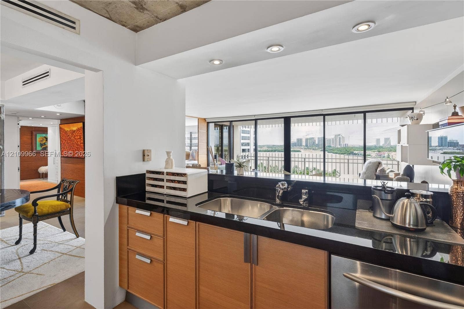 Kitchen featuring wood-finish cabinetry, black countertop, dual-basin stainless steel sink, recessed lighting, and raw concrete ceiling detail