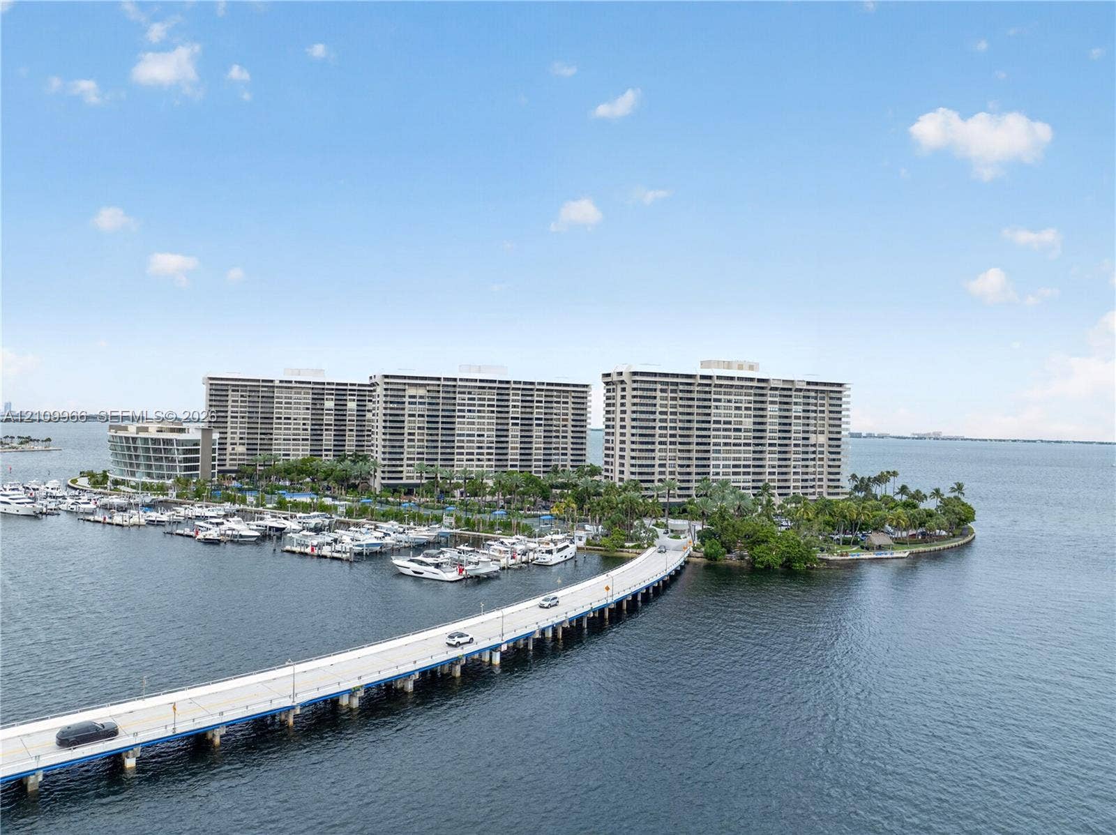 Waterfront high-rise community featuring a private marina, paved causeway access, and established tropical landscaping