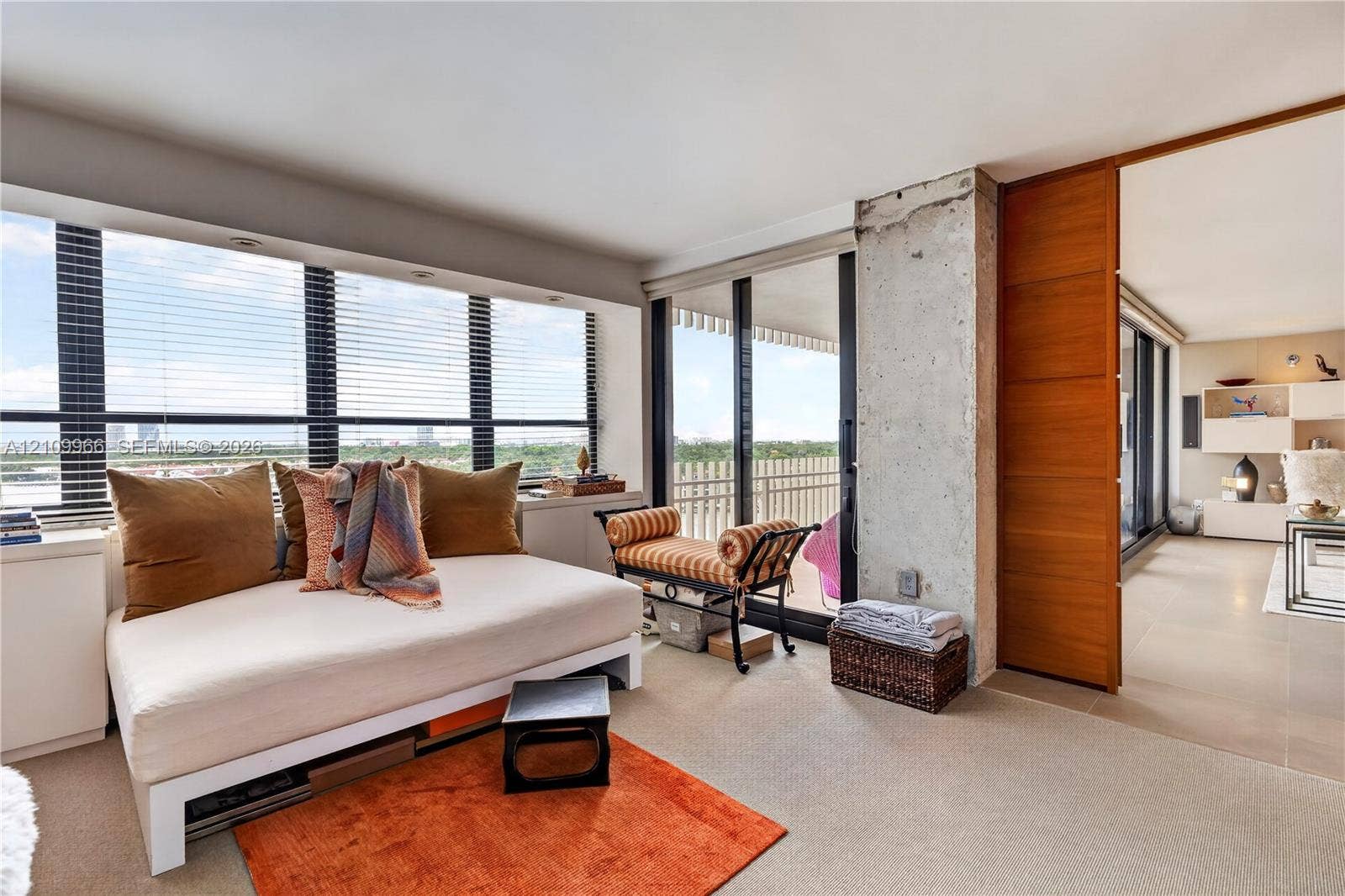 Floor-to-ceiling windows, exposed concrete structural column, sliding wood-finish door, and integrated lighting fixtures
