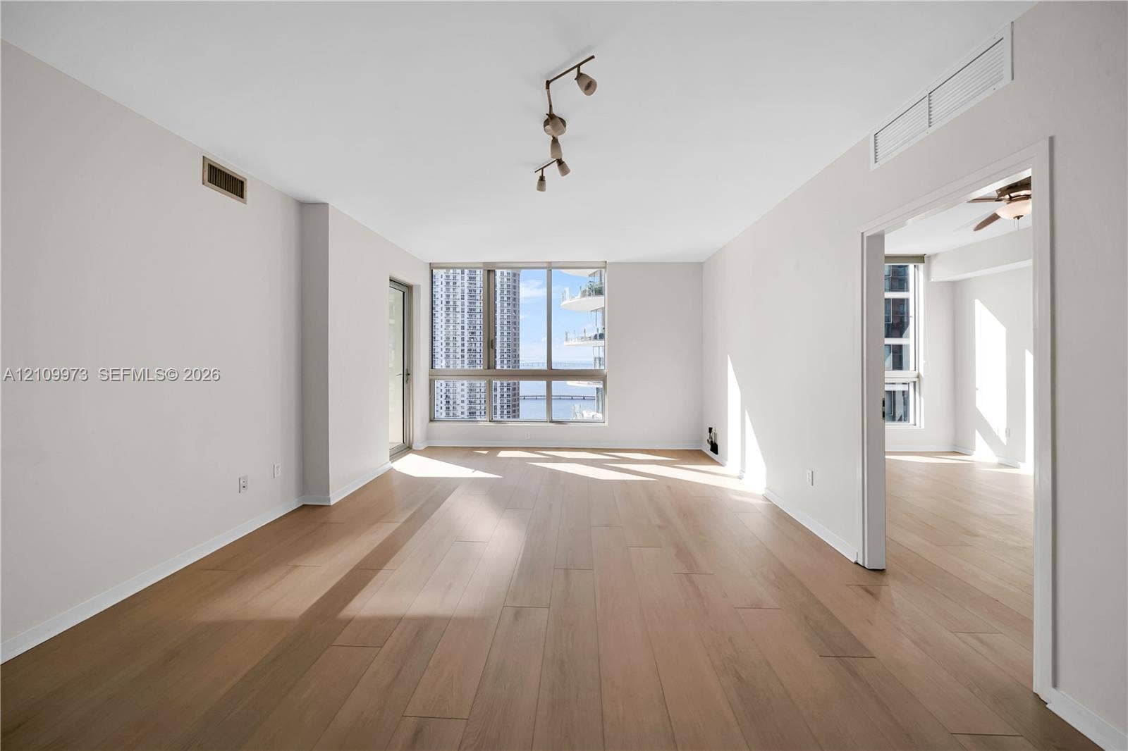 300 S Biscayne Boulevard, #T-1806, Miami, Miami, FL 33131 Open-concept living space featuring wood-finish flooring, floor-to-ceiling windows, and multi-directional track lighting