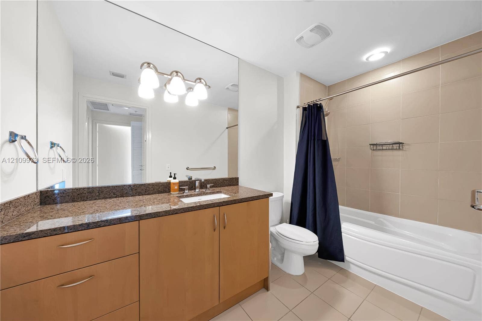 300 S Biscayne Boulevard, #T-1806, Miami, Miami, FL 33131 Bathroom featuring light wood cabinetry, stone-finish countertop with an integrated basin, large wall-mounted mirror, and a tub-shower combination with floor-to-ceiling tile surround