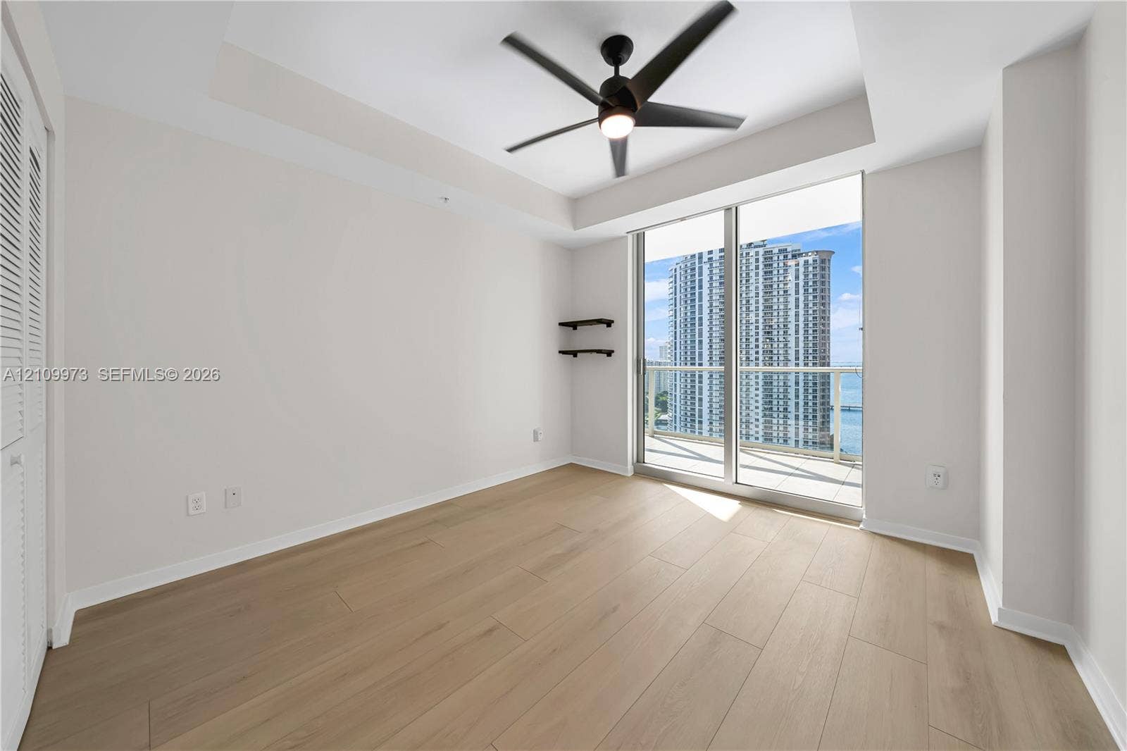 300 S Biscayne Boulevard, #T-1806, Miami, Miami, FL 33131 Room featuring wood-finish flooring, a coffered ceiling with a built-in fan, and floor-to-ceiling glass sliding doors opening to a balcony