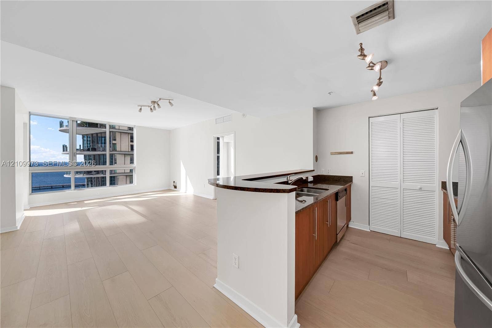 300 S Biscayne Boulevard, #T-1806, Miami, Miami, FL 33131 Open-concept living space featuring wood-finish flooring, floor-to-ceiling windows, natural stone kitchen countertops, and track lighting