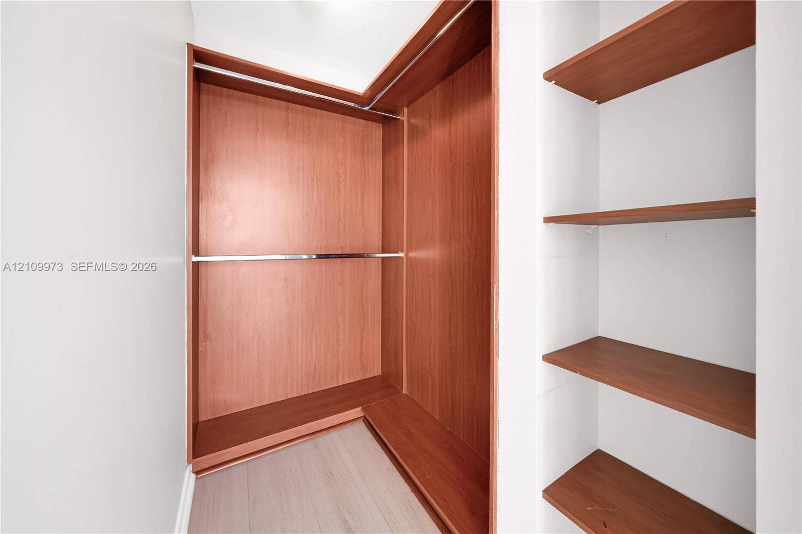 300 S Biscayne Boulevard, #T-1806, Miami, Miami, FL 33131 Built-in closet featuring wood-finish shelving, an L-shaped hanging rod system, and neutral wood-finish flooring