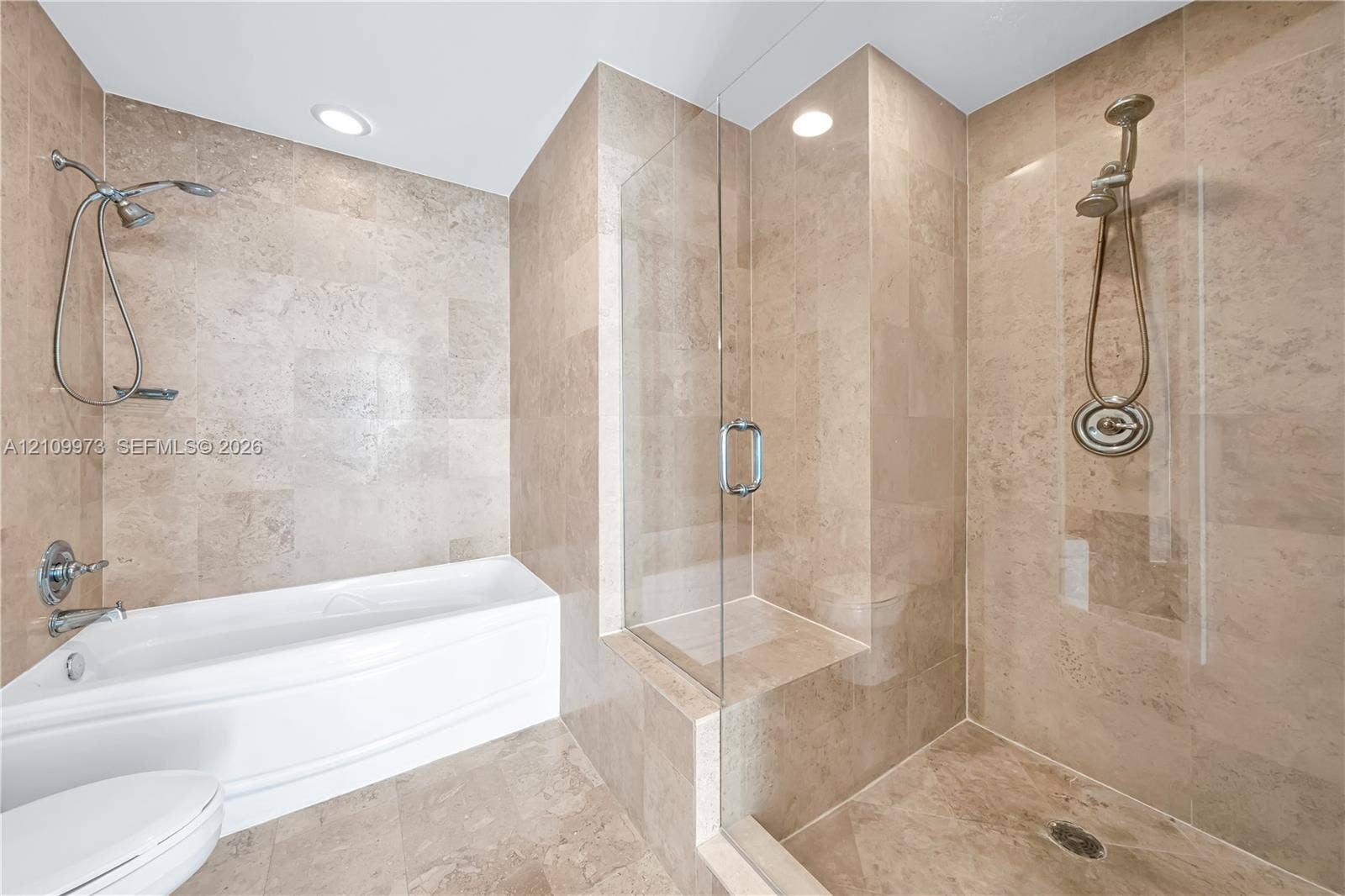 300 S Biscayne Boulevard, #T-1806, Miami, Miami, FL 33131 Stone tile wall surfacing, glass-enclosed shower stall with a built-in bench, deep soaking tub, and polished chrome hardware